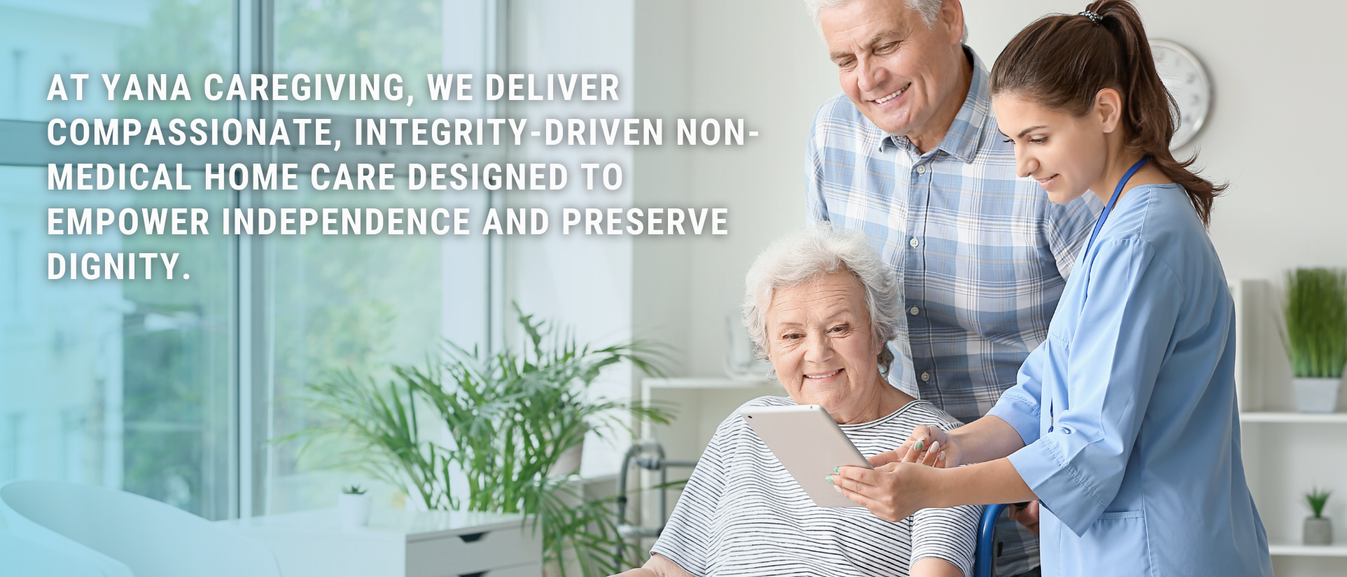 A caregiver showing a tablet to an elderly woman with a nurse and her son in a healthcare setting with large windows and green plants.