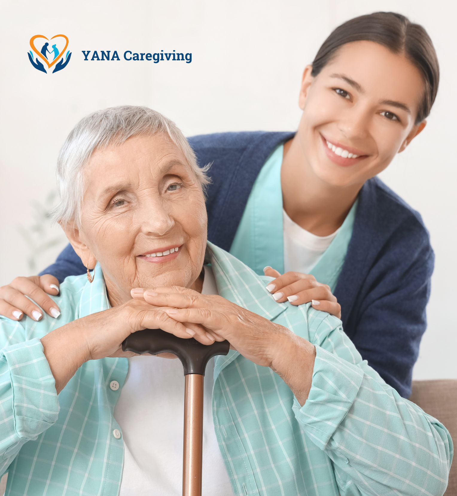 A smiling elderly woman with gray hair, wearing a light green plaid shirt, sitting with a cane, and a young female caregiver with dark hair, smiling, standing behind her with her hands on the woman's shoulders. The caregiver is wearing a light blue uniform and a navy blazer. The background is bright and neutral, with a logo in the top left corner that says "YANA Caregiving" with a heart and hands design.