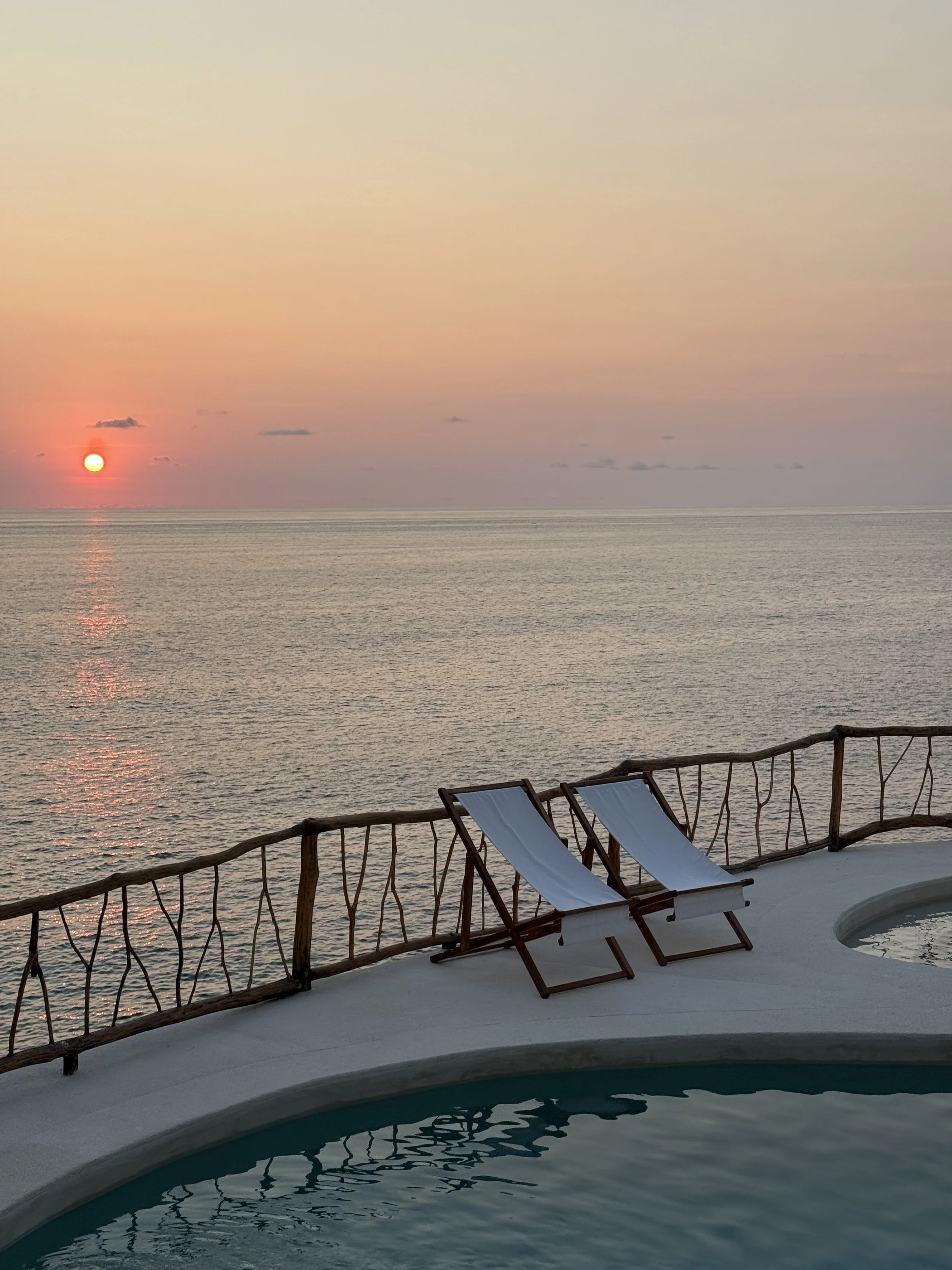 Sunset view from ZAIA private cliffside villa overlooking the Pacific Ocean, with pool and lounge chairs on the west coast of Mexico, near Zihuatanejo.