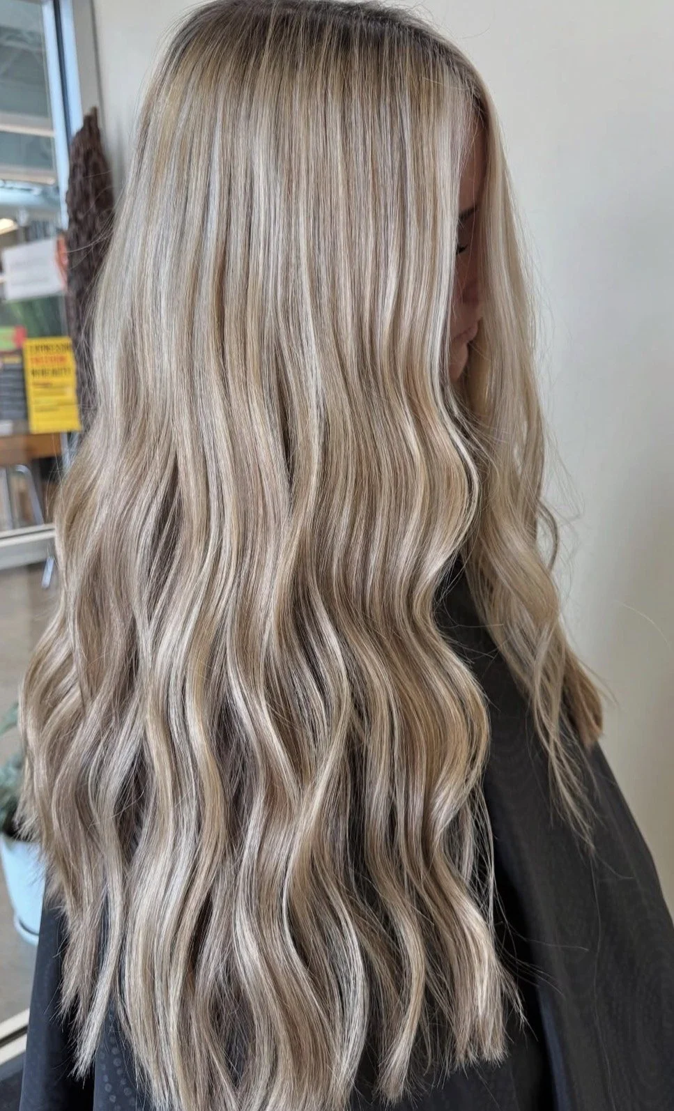 A woman with long, wavy blonde hair that has highlights.
