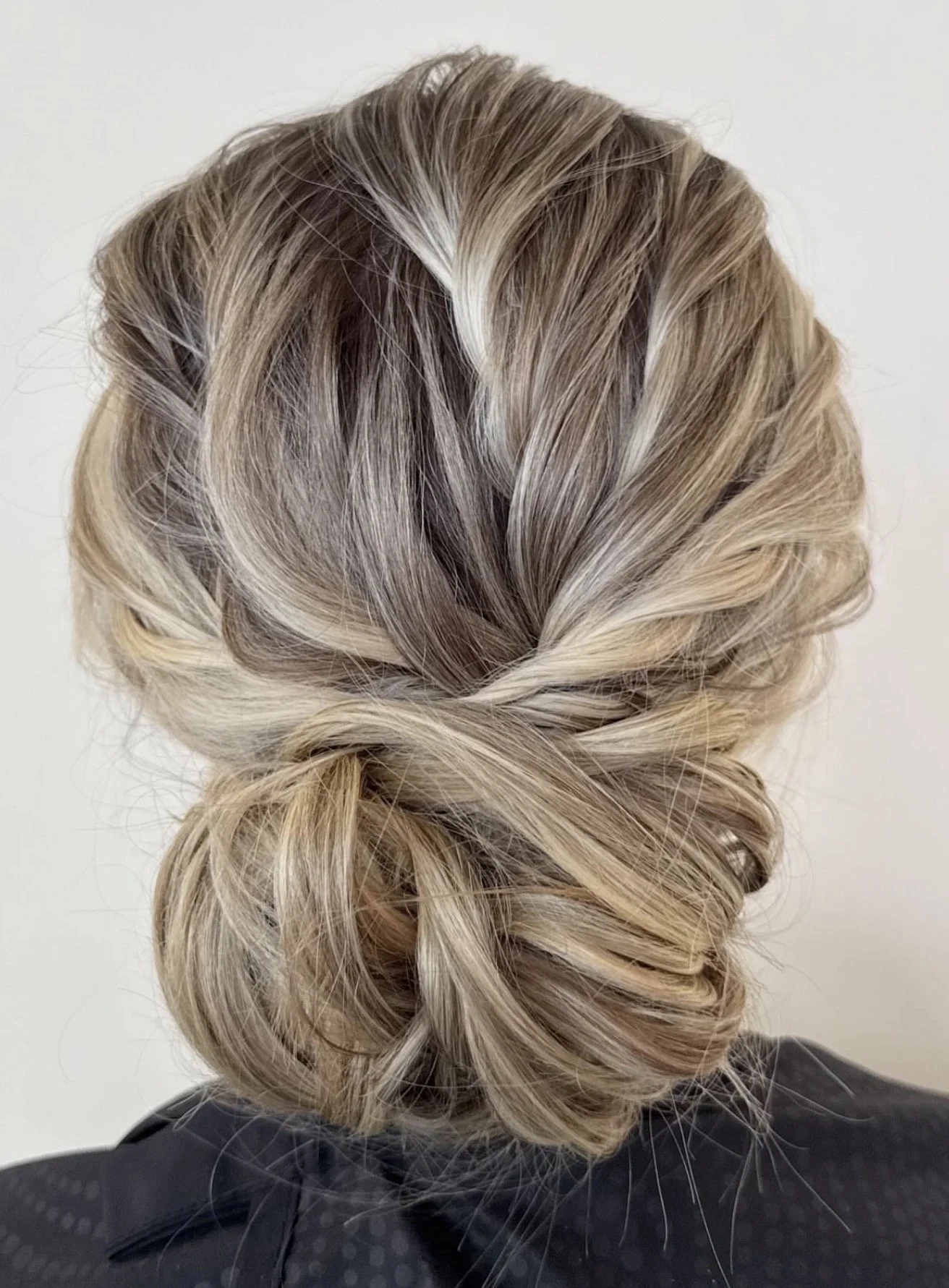 Elegant blonde updo with woven and twisted sections, styled into a low bun.