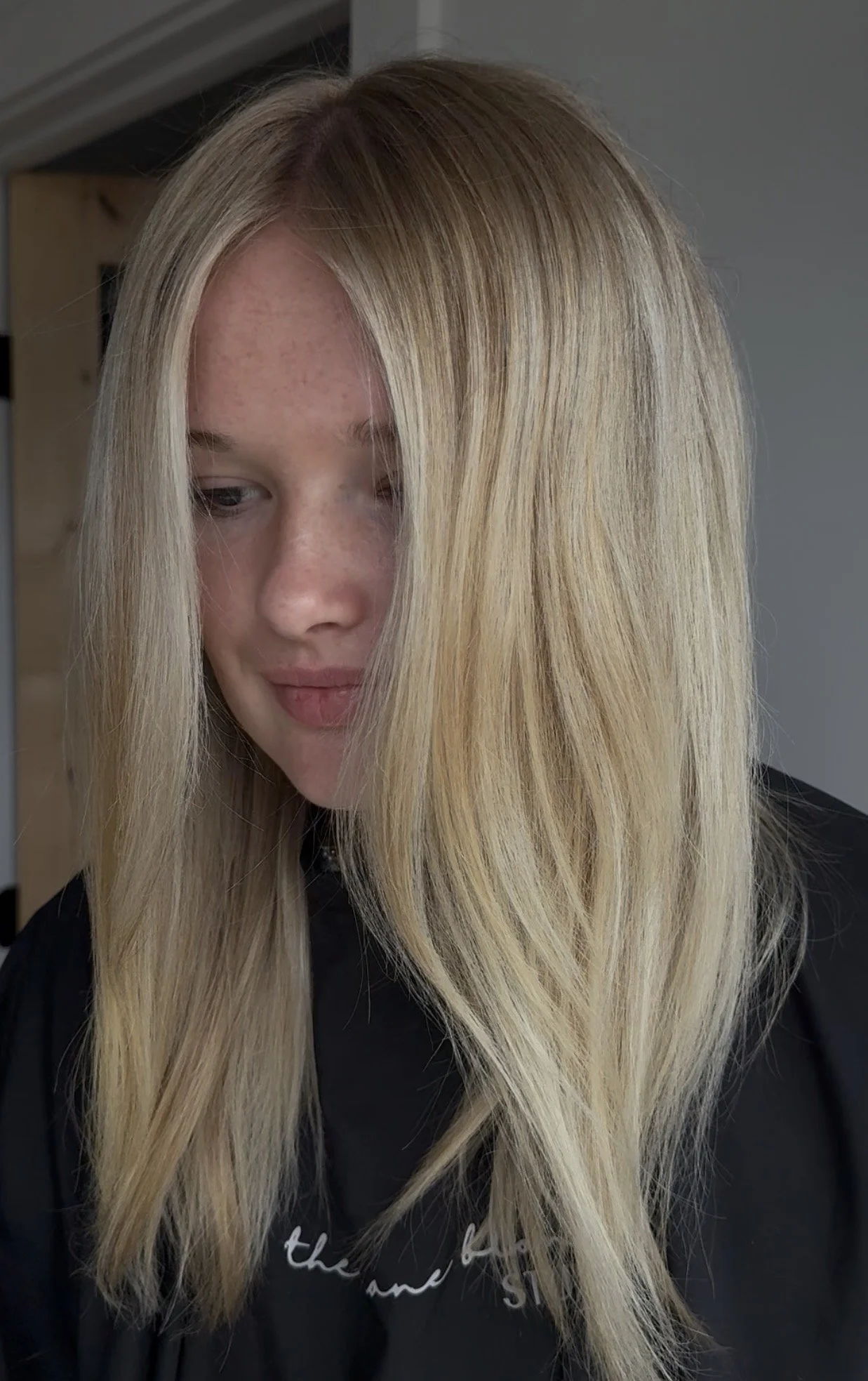 Close-up of a young woman with long, straight blonde hair, looking down.