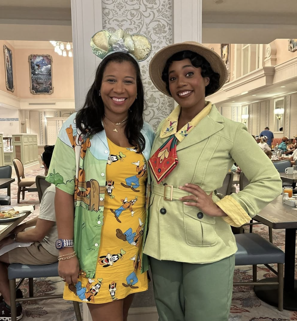 Two women dressed in colorful vintage fashion posing inside a restaurant.