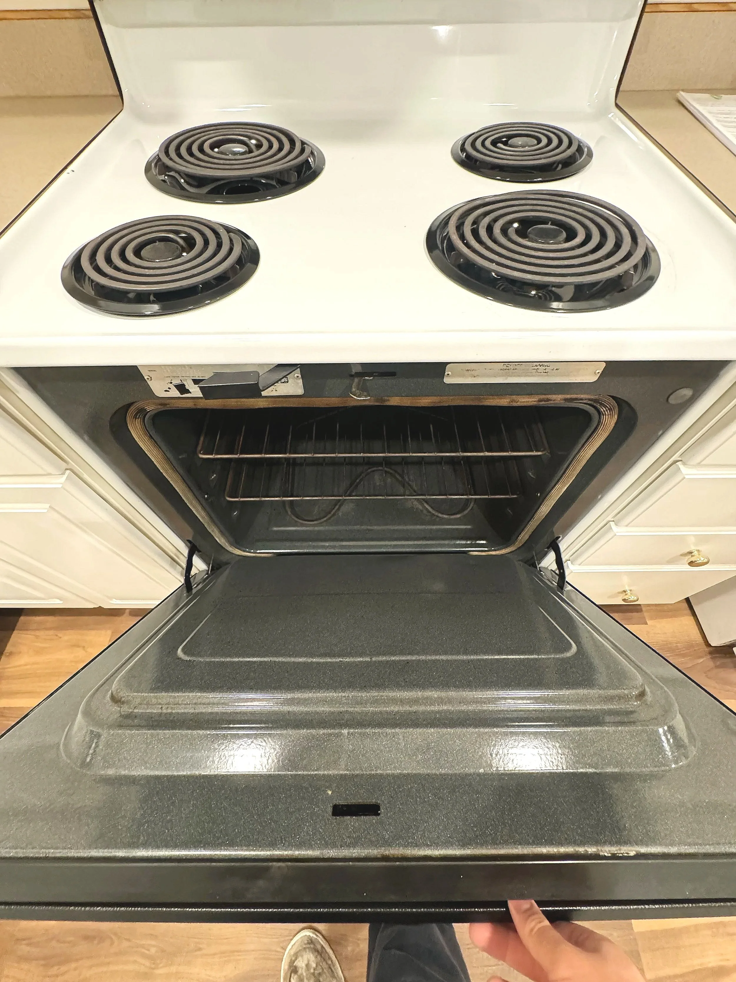 Open oven door with four coil burners on stovetop.