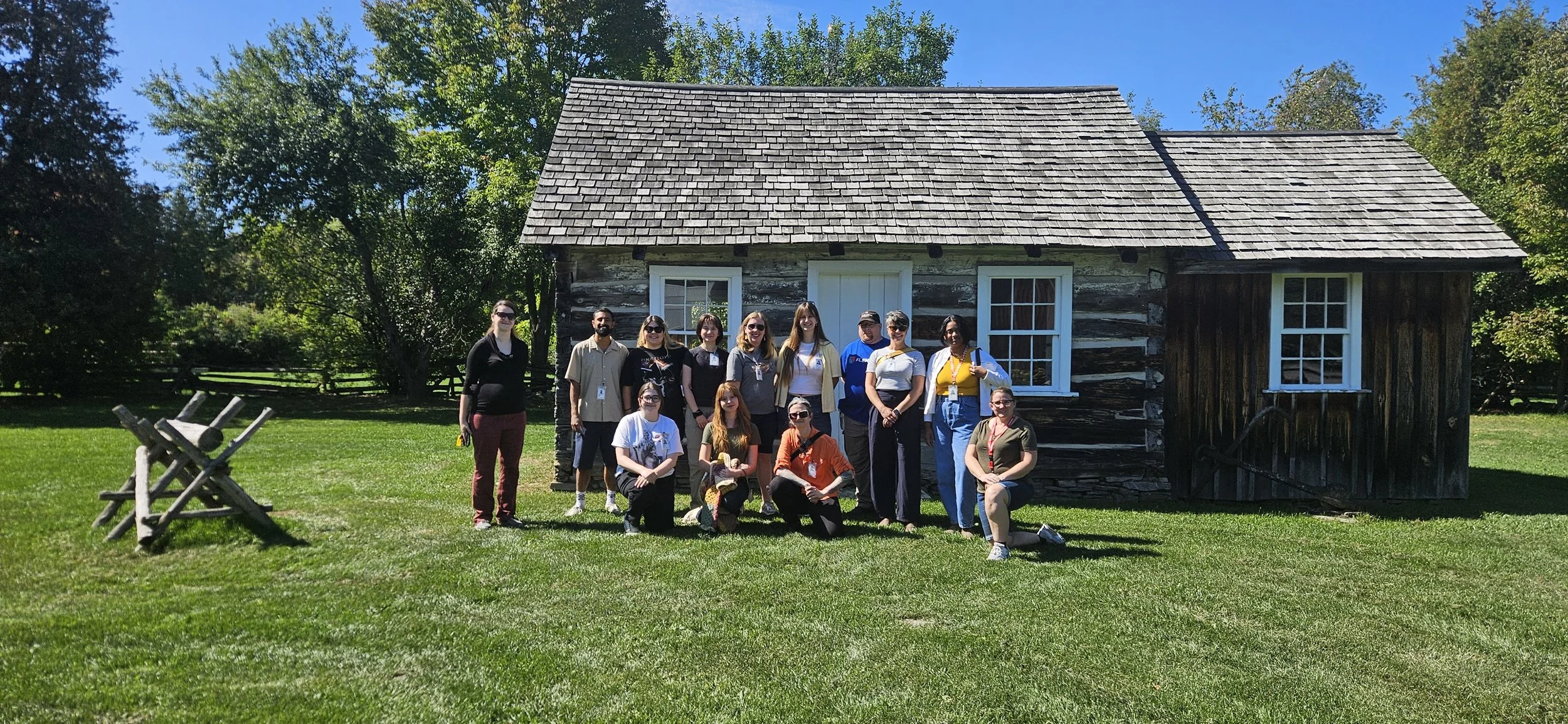 Museum Management & Curatorship students standing in front of the Ayotte cabin at Lang Pioneer Village and Museum