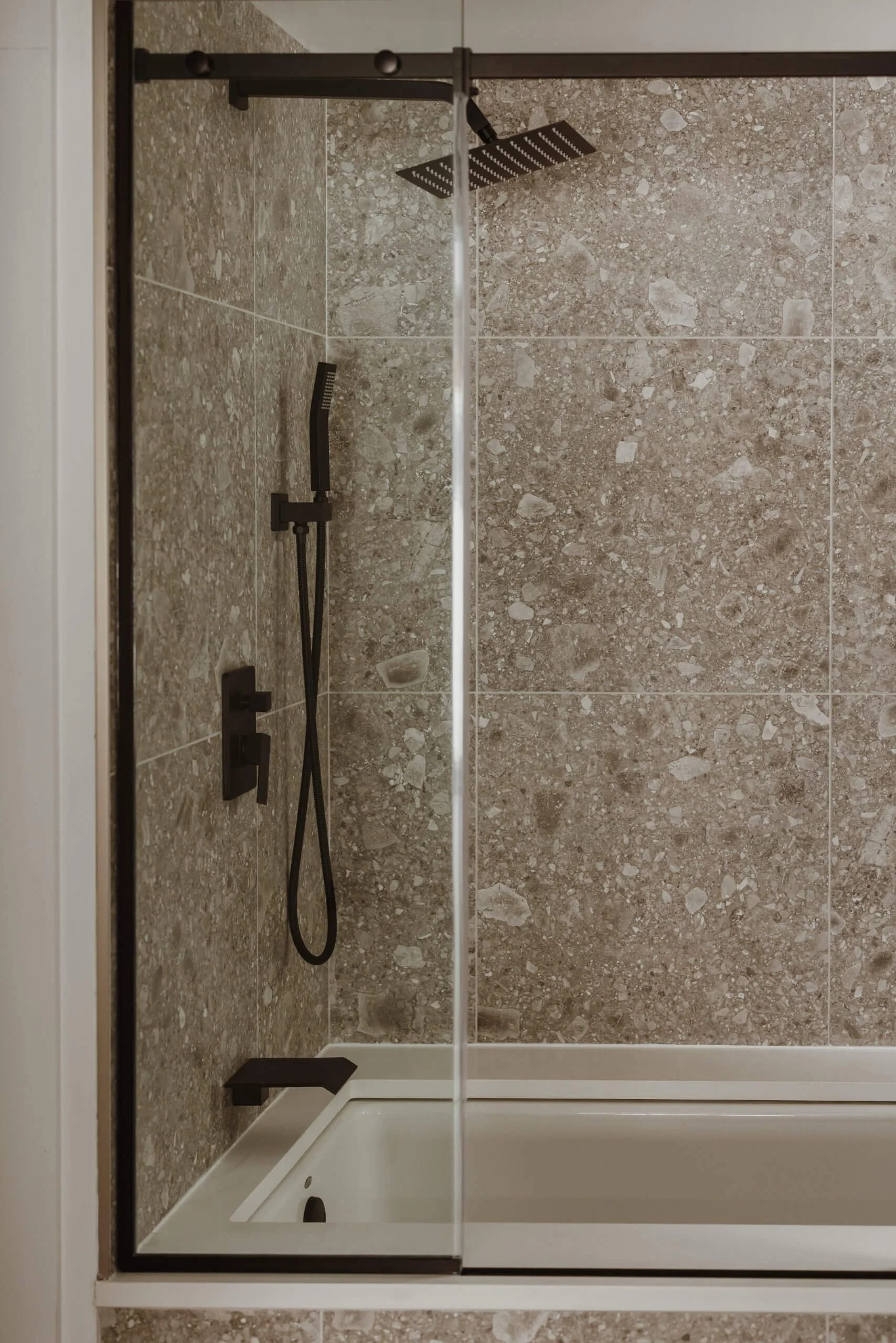 Shower with a rainfall showerhead, handheld shower, and soap dish in a tiled bathroom.