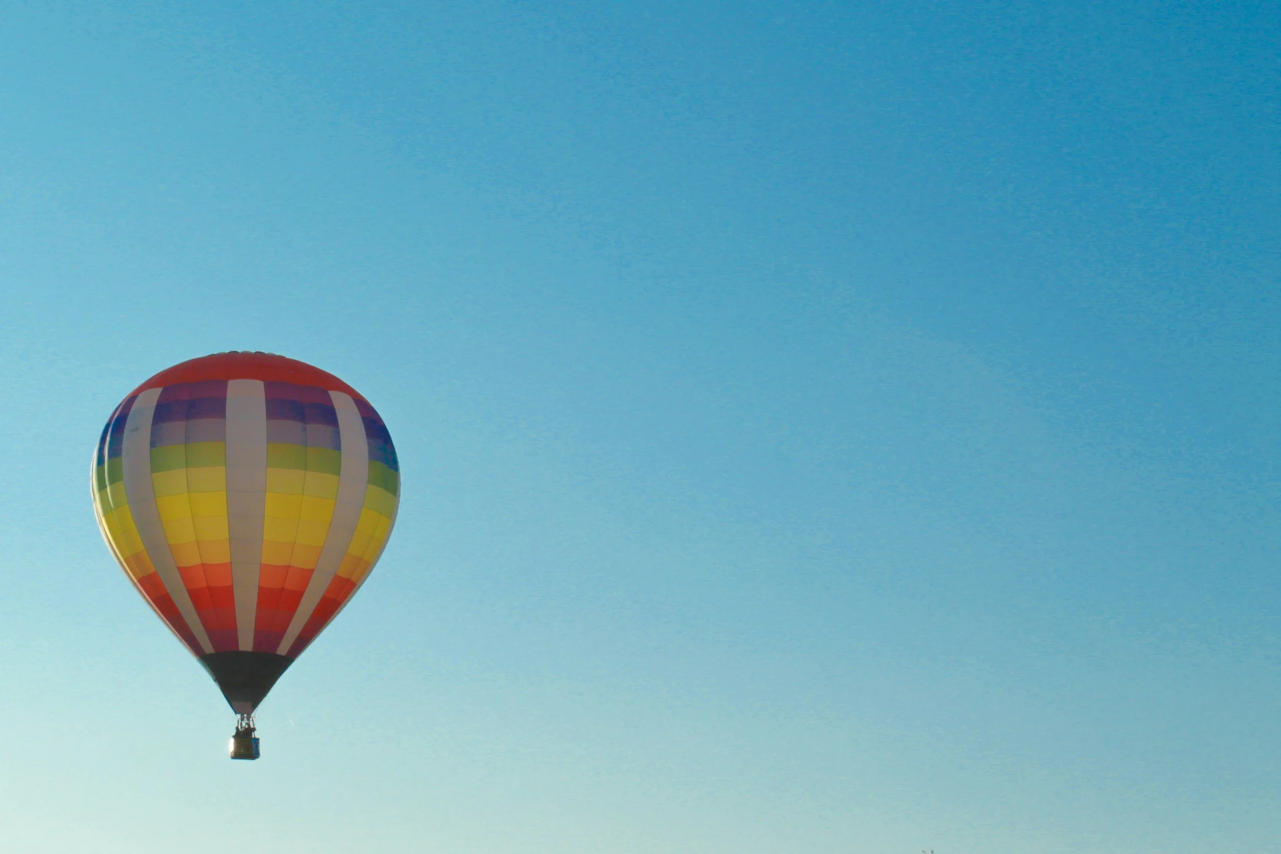 Single hot air balloon in blue sky.