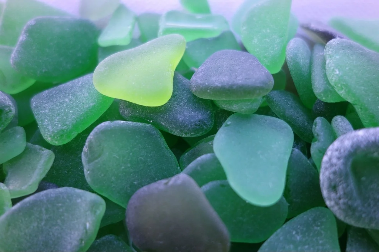 Close-up of frosted sea glass pieces in green, aqua, and grey tones.