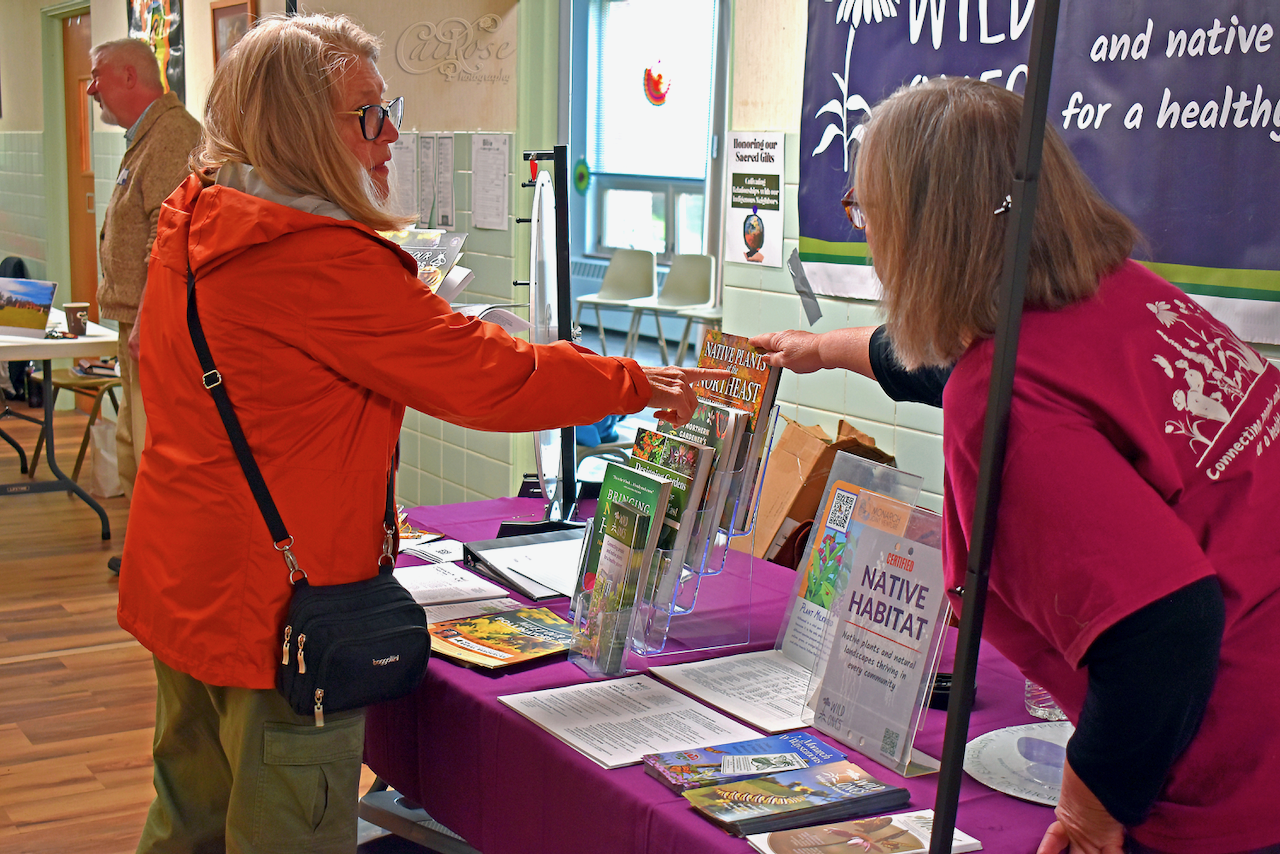 Women Discussing Wanted Book on Table, credited.png