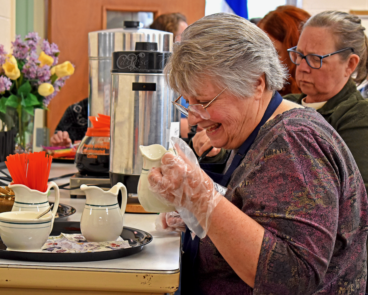 Volunteer Smiling and Bringing Creamer to Kitchen, credited.png