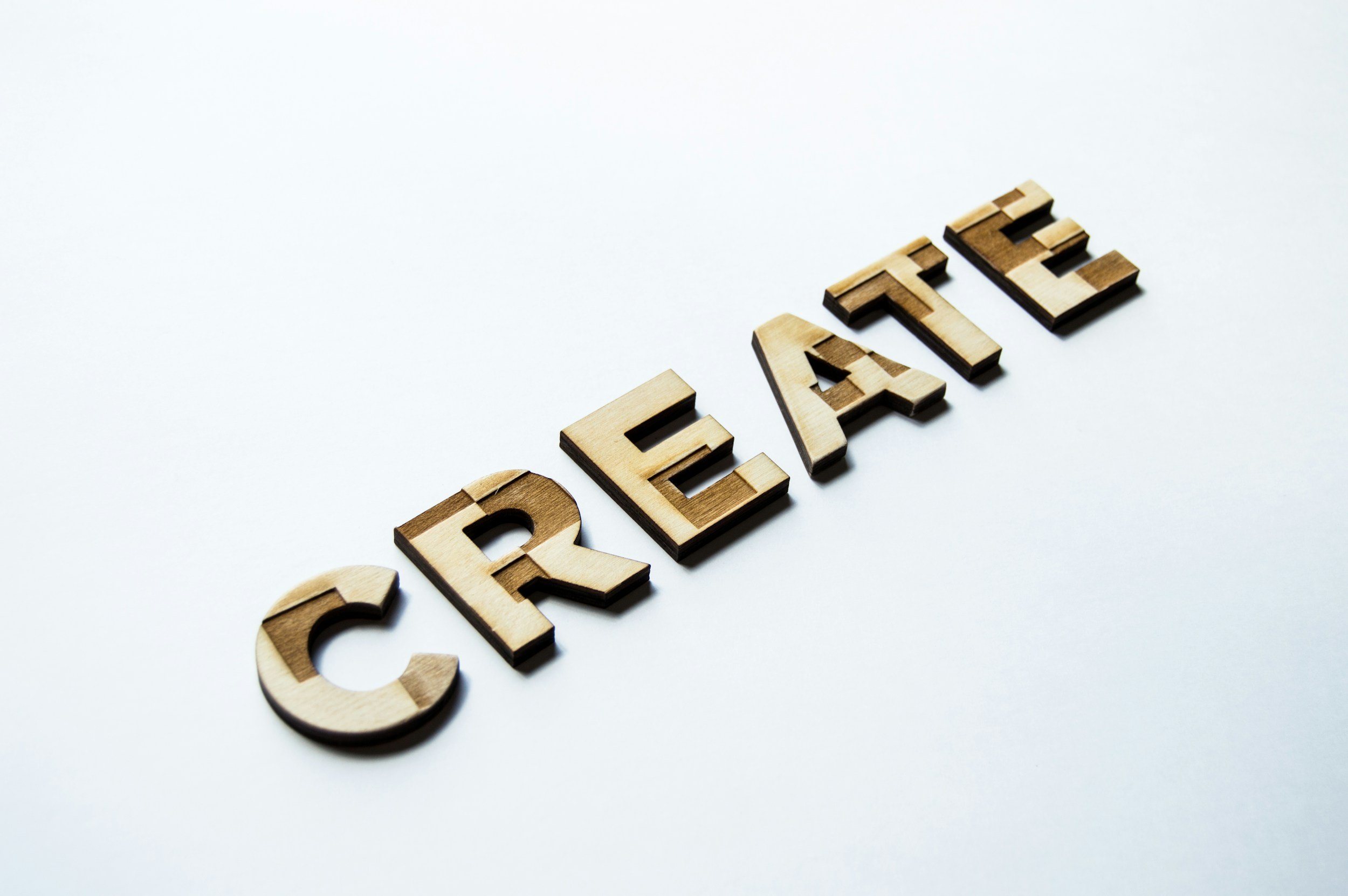 Wooden letters spelling out the word 'CREATE' on a white surface.
