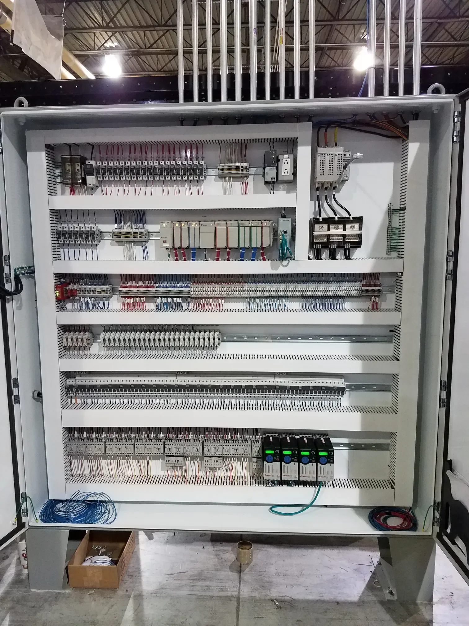 A large industrial control panel with various electrical components, wires, and circuit boards inside a metal enclosure.
