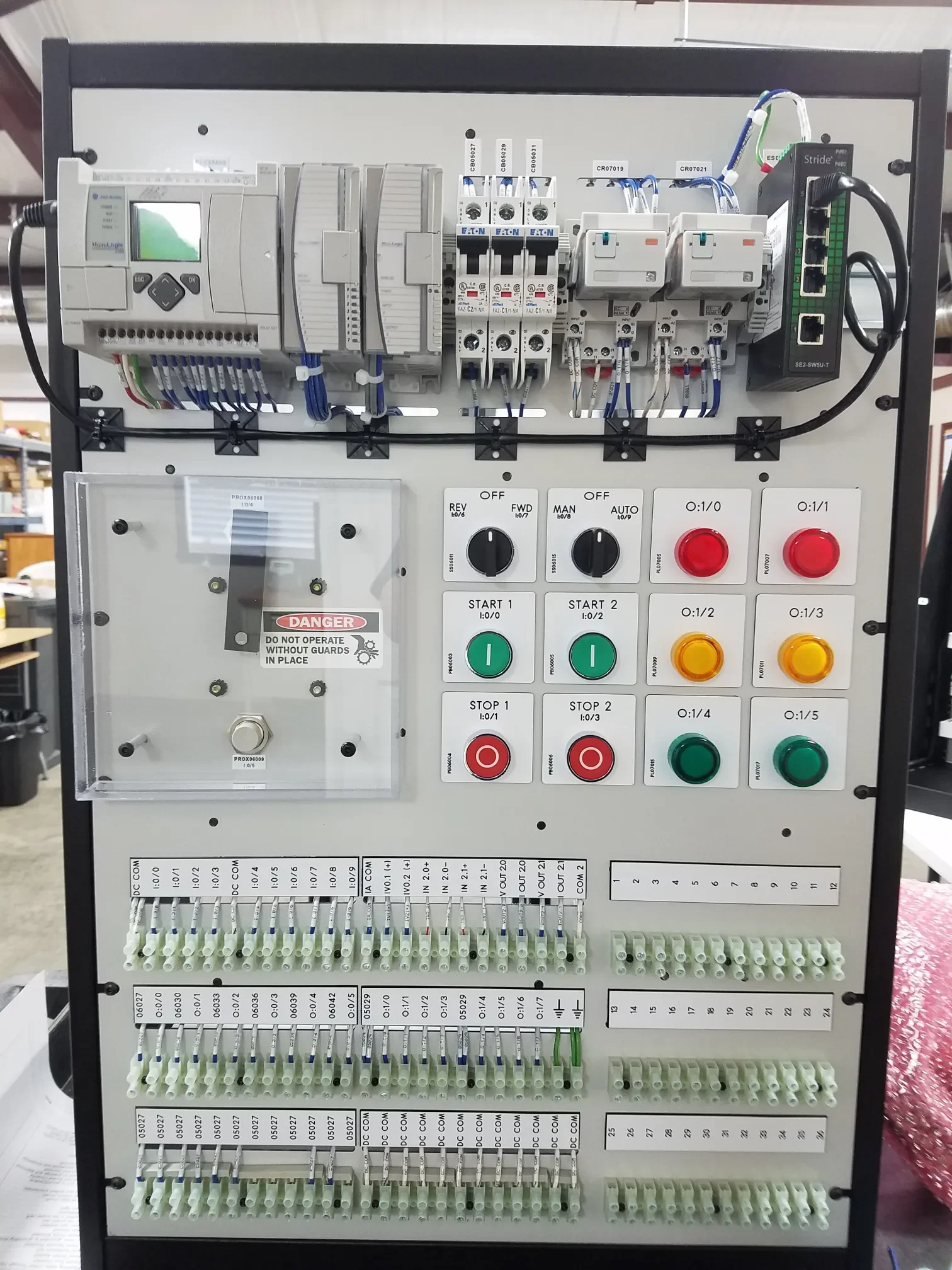 An industrial control panel with various switches, buttons, wiring, and circuit breakers organized in sections.