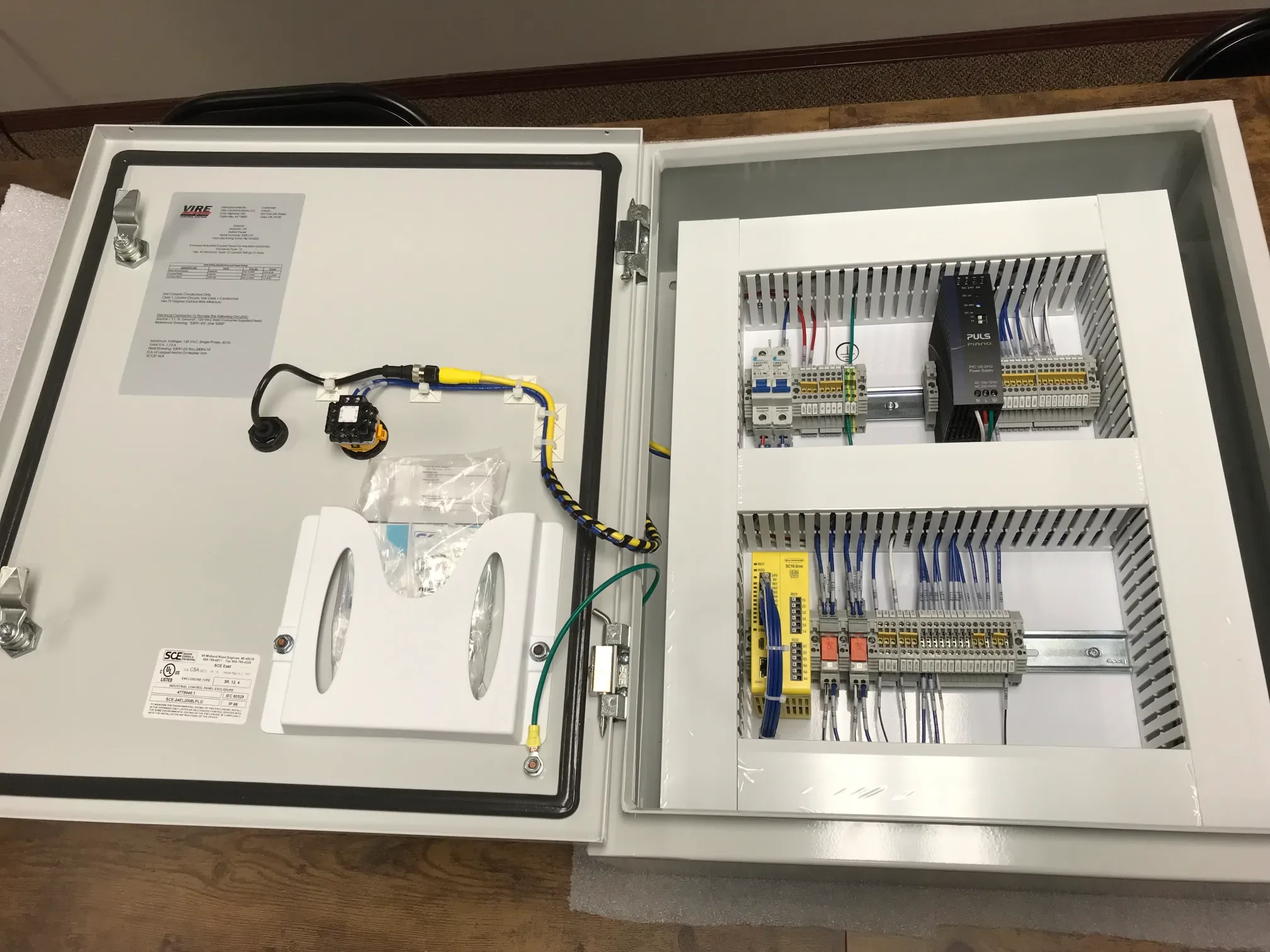 Open electrical control panel with various wiring, relays, and circuit components inside.