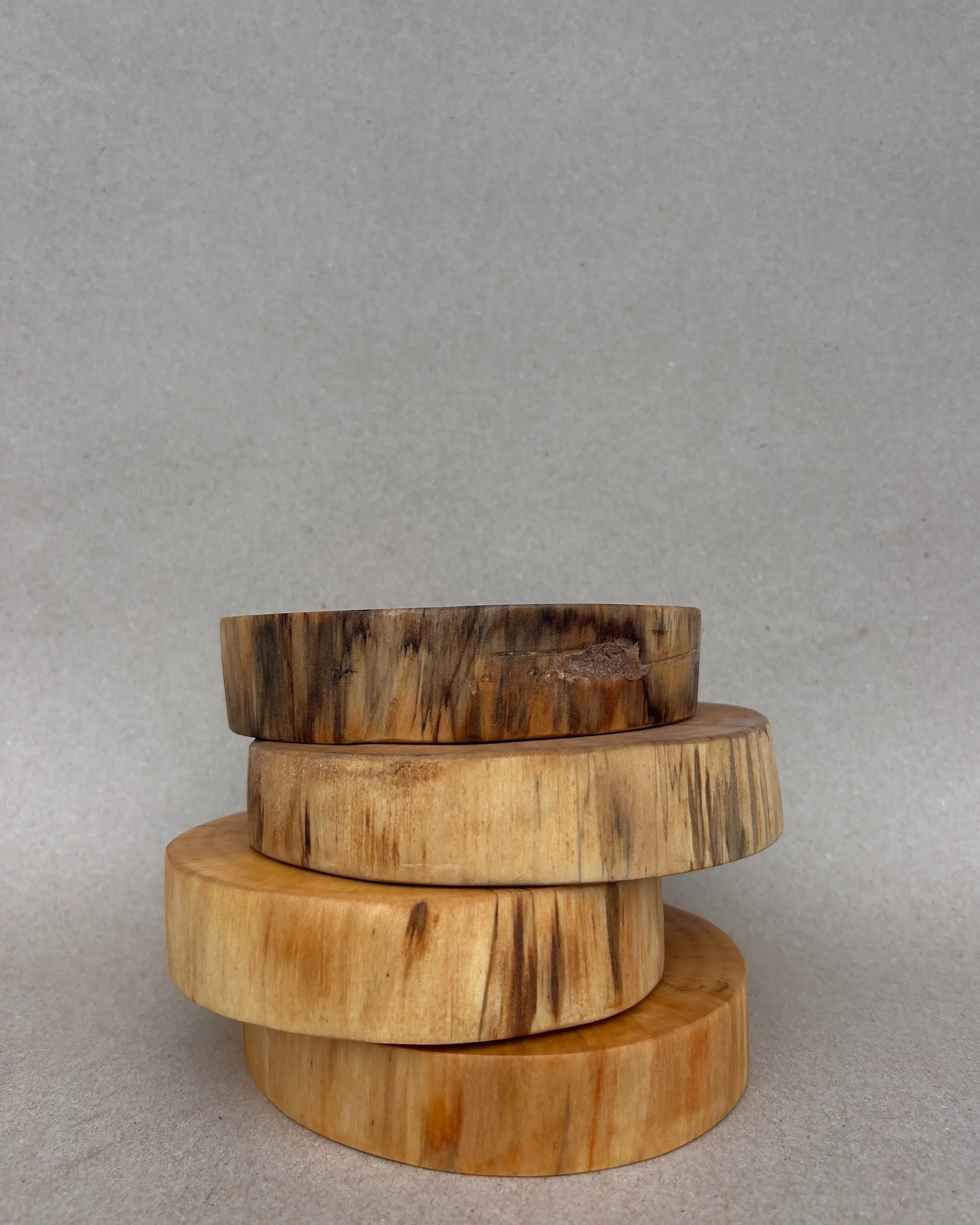 Four wooden circular slices stacked on top of each other against a plain background.