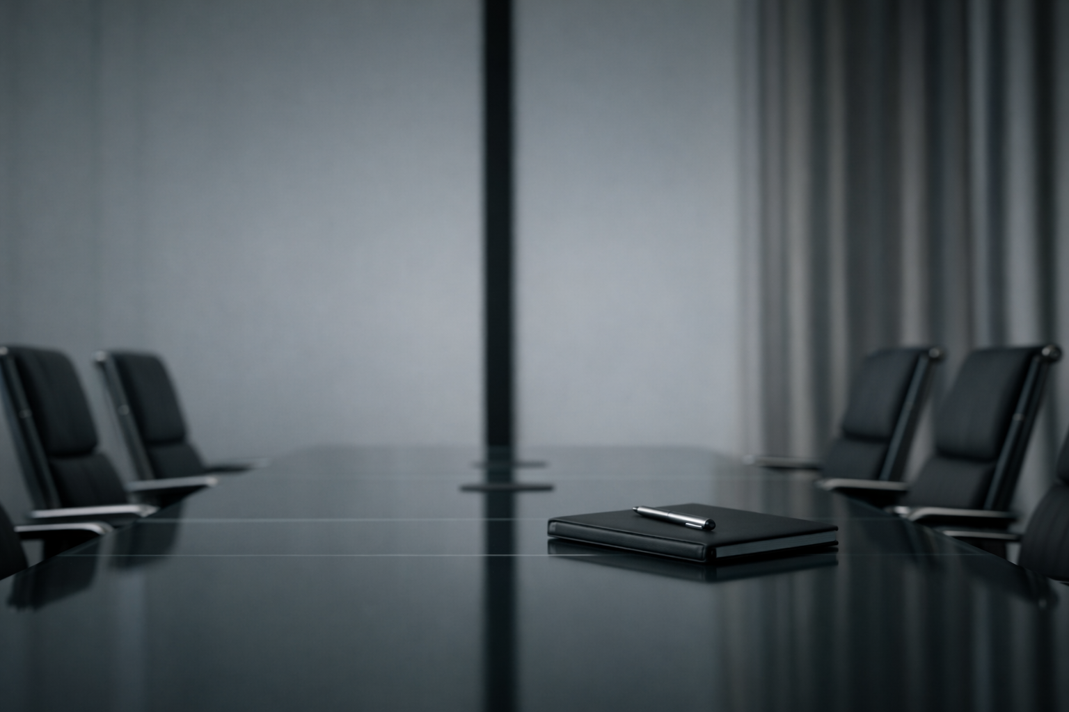 Empty conference room with a black table, a notepad, and a pen in the center, surrounded by black chairs, with a gray wall and curtains in the background.