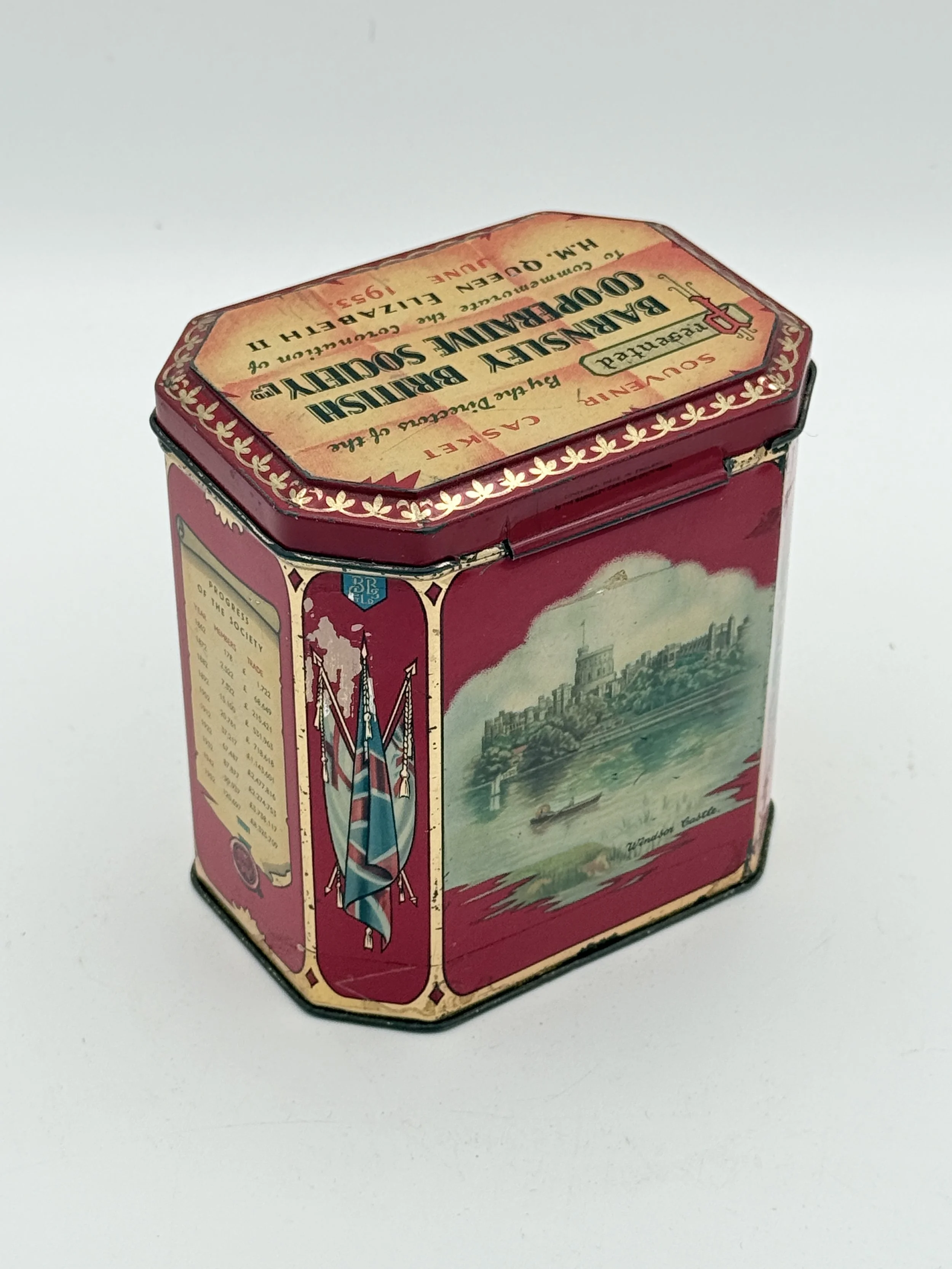 A vintage tin container with London-themed artwork, including flags and a cityscape along a river.