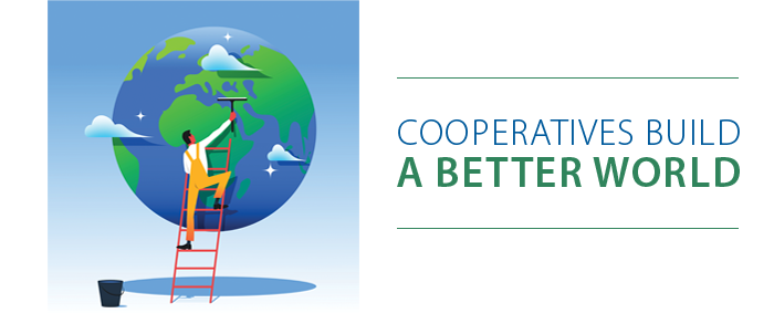 Person on ladder painting a green tree on a globe with the text 'Cooperatives Build a Better World'.