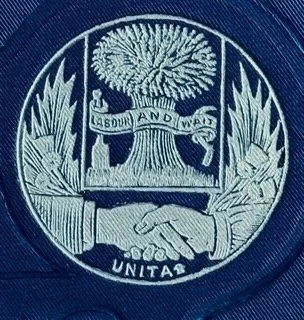 Close-up of a seal featuring a tree, a handshake, and a banner with the words 'Absurd and was' and 'Unita'.