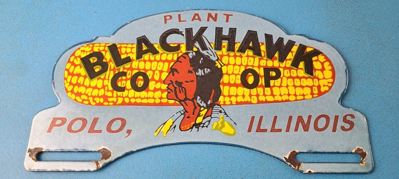 Vintage metal sign for Blackhawk Co-op, Polo, Illinois, with a stylized Native American chief illustration and bright yellow and orange background.
