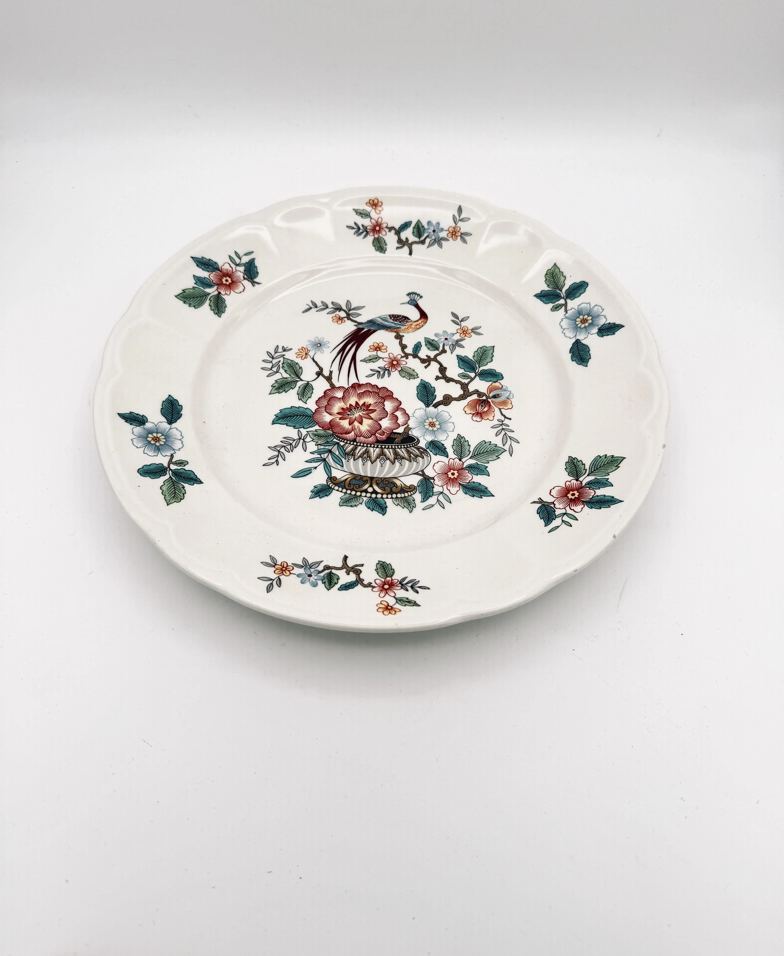Decorative ceramic plate with a floral and bird pattern on a white background.