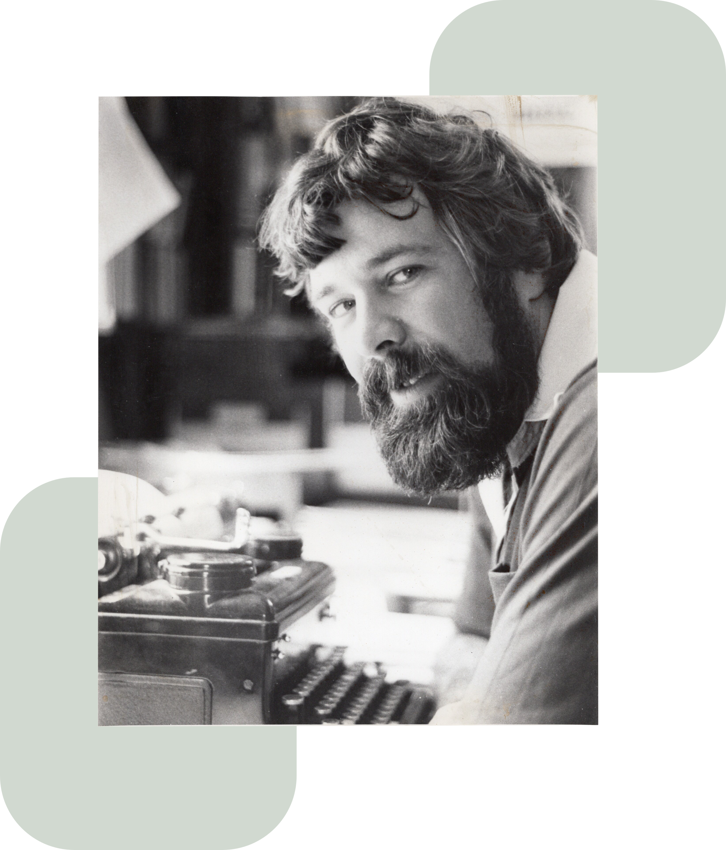 Black-and-white photo of a bearded David J Thompson in front of assorted papers and a typewriter.