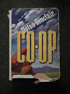 A worn paperback book titled 'C.O.P' by Upton Sinclair with a colorful illustrated cover of mountains, sky, and landscape.