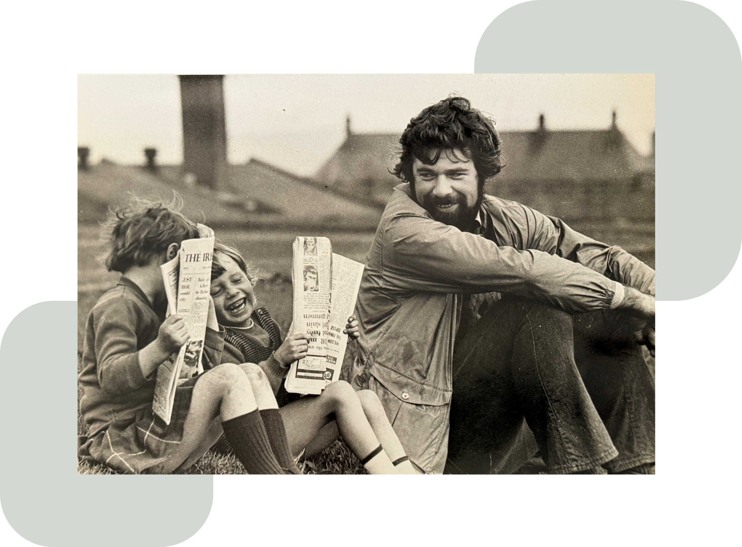 Vintage black-and-white photo of a smiling bearded man, David J Thompson, and two children sitting outdoors, reading newspapers in the UK.