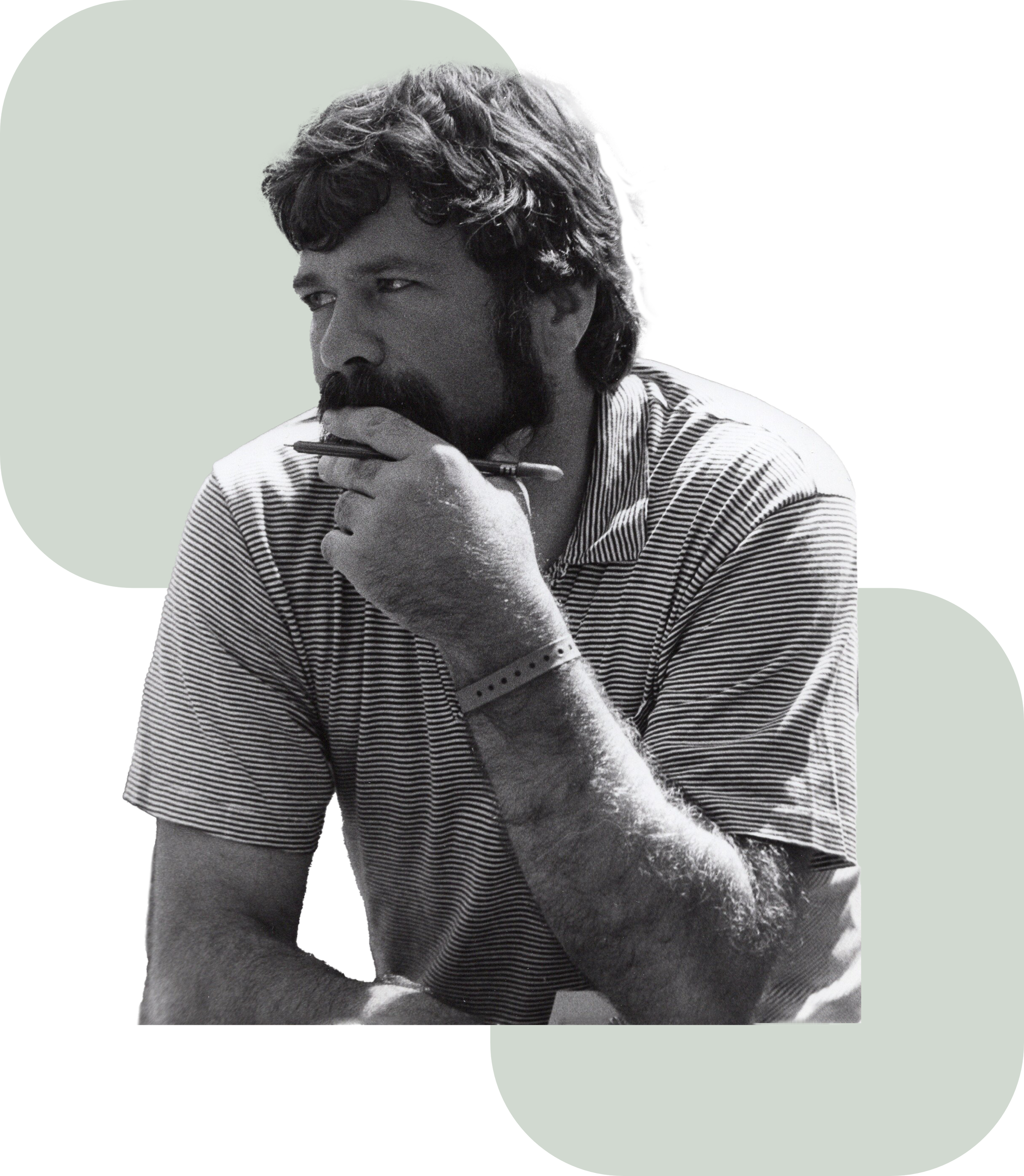Black-and-white portrait of a bearded man, David J Thompson, in sunglasses and a striped shirt holding a pen near his chin