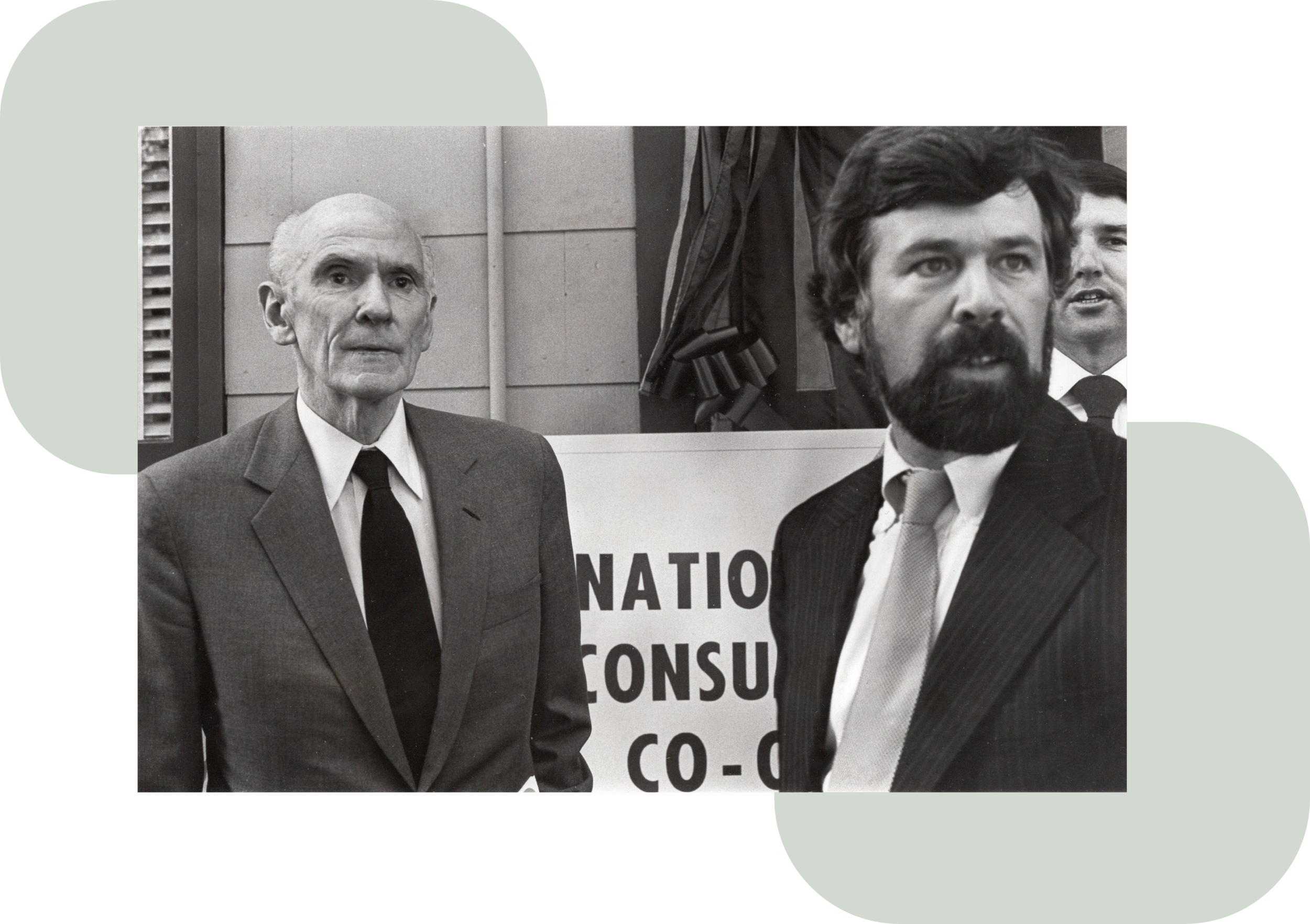 Black-and-white photo of two men in suits at a co-op promoting social event.