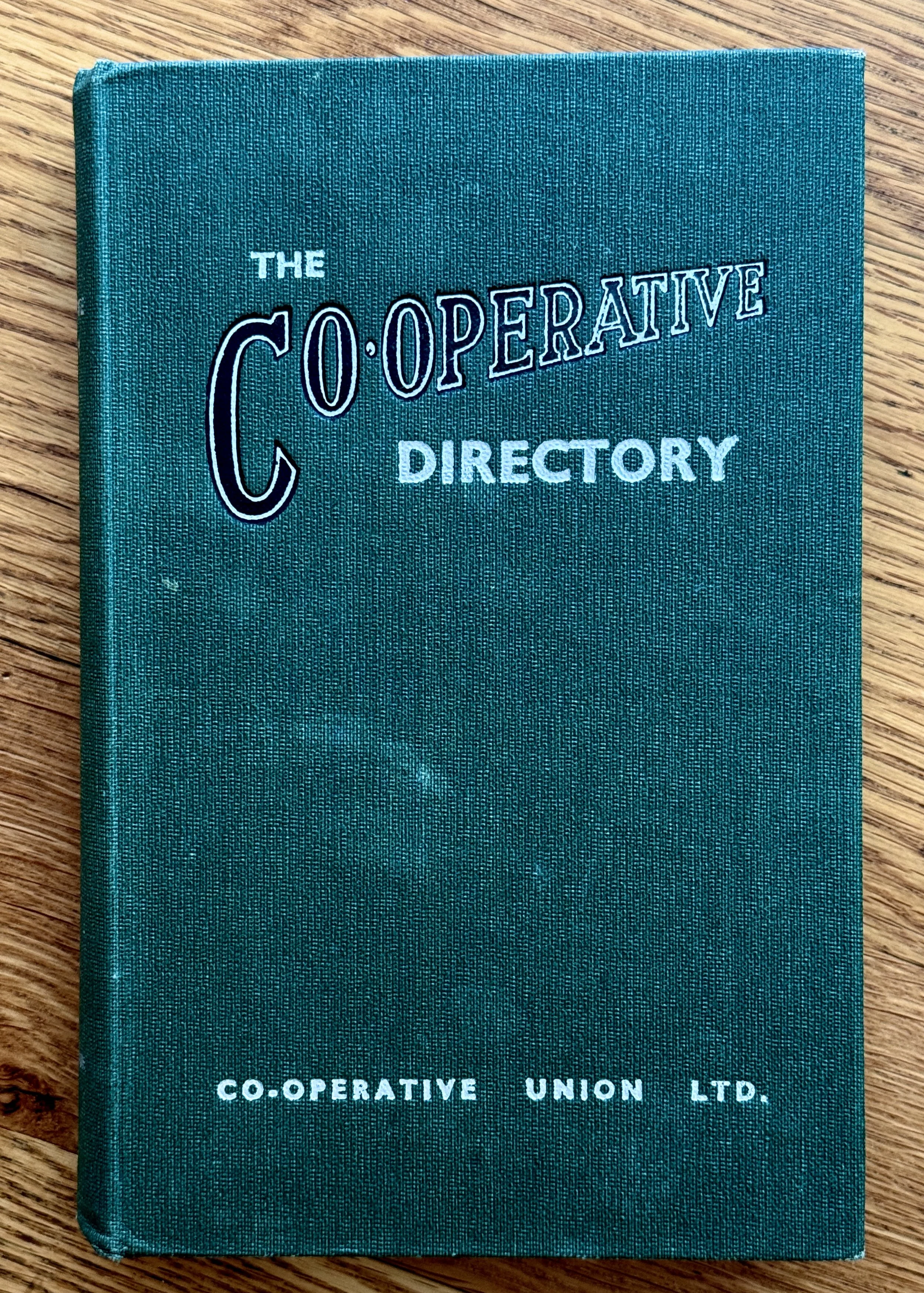 A teal hardcover book titled 'The Co-operative Directory' with the publisher 'Co-operative Union Ltd.' on a wooden surface.