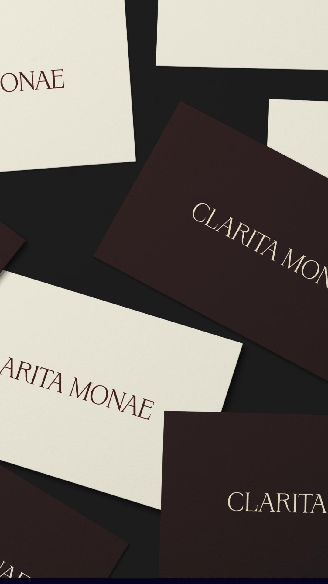 Business cards with the name 'Clarita Monae' printed on them in elegant font, arranged on a black background.