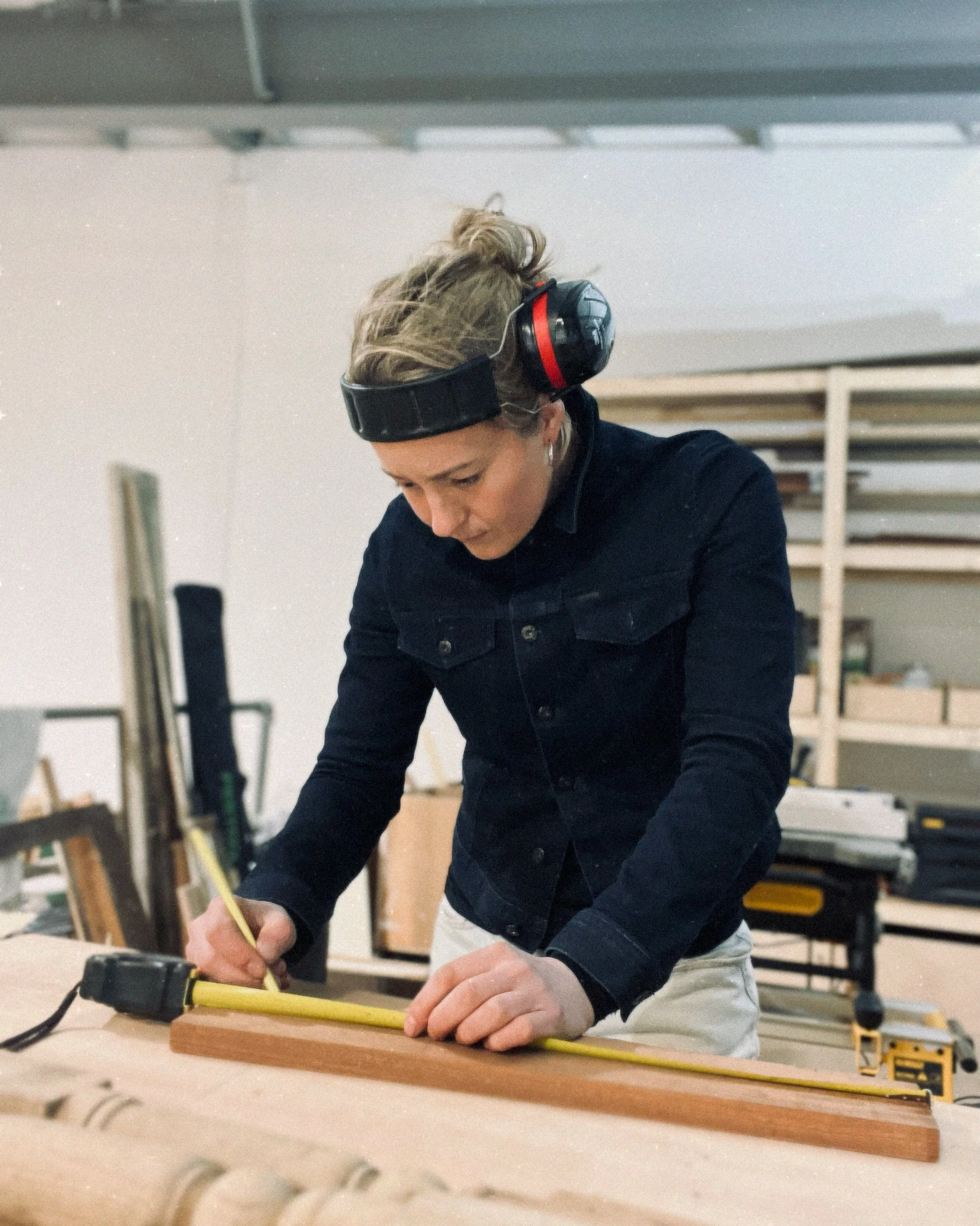 female woodworker marking out some wood in her workshop