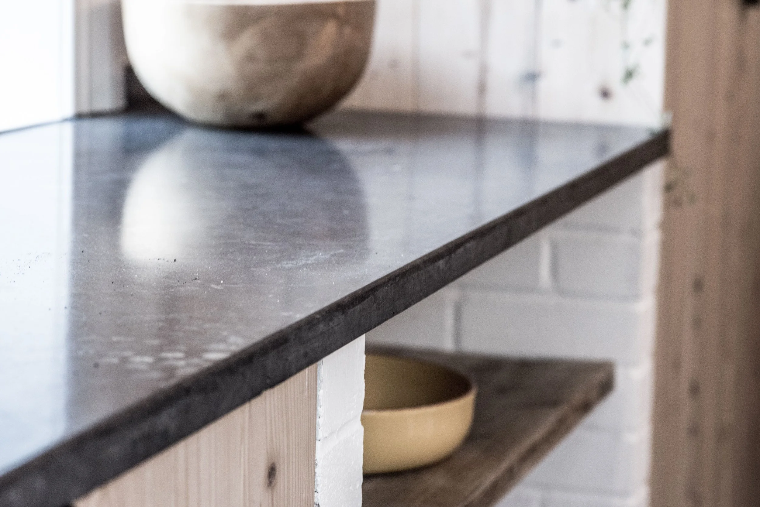 Close-up of a kitchen counter with a ceramic bowl on top and another in a lower shelf.