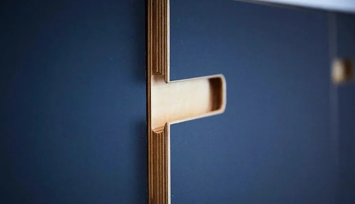 Close-up of a blue cabinet with a sliding drawer partially open, showing a wooden handle.