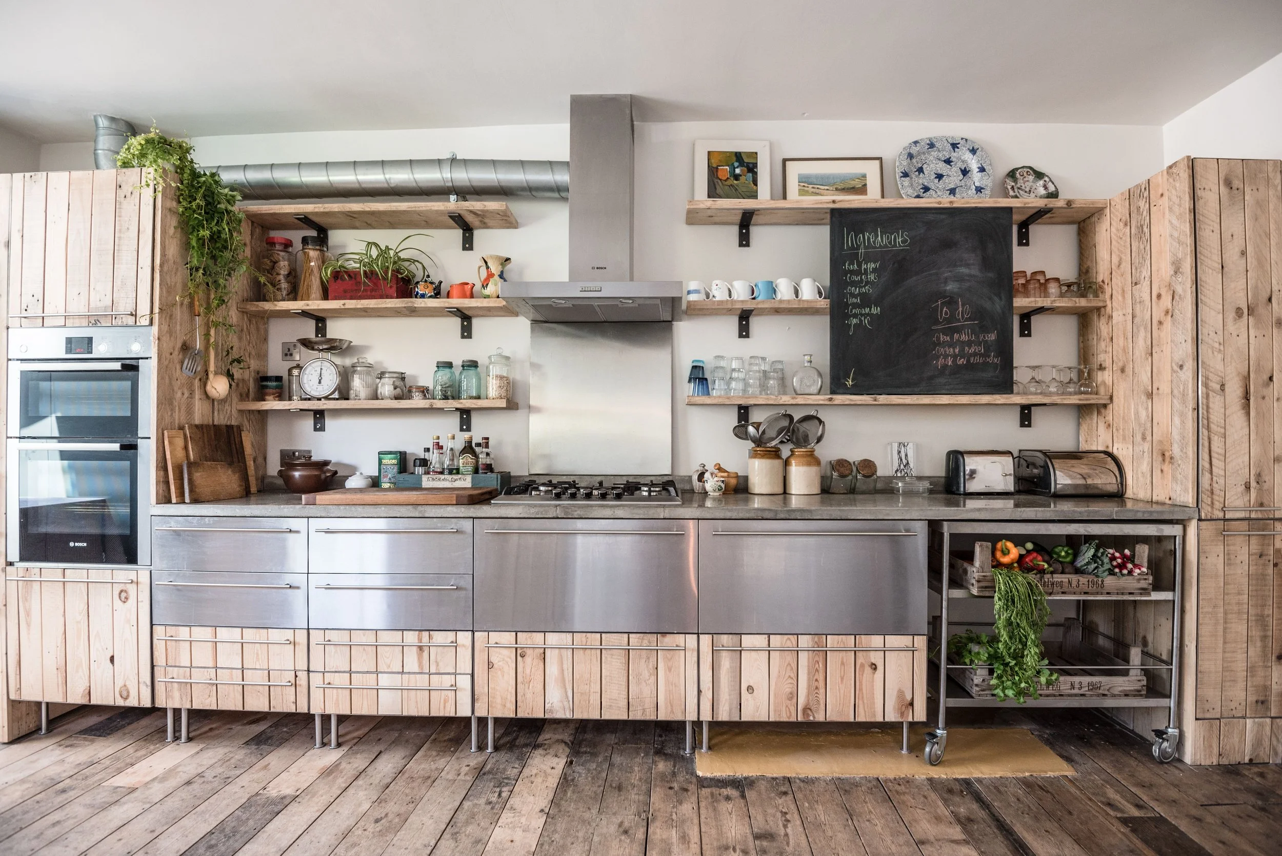 Reclaimed wooden and stainless steel kitchen fronts. scaffolding shelves and chalk board.