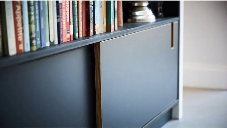 Close-up of a blue bookshelf with books on top and a sliding cabinet door below.