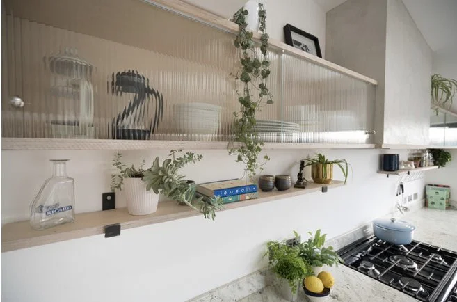 Kitchen countertop with plants, bowls, and a blue pot near a stove.