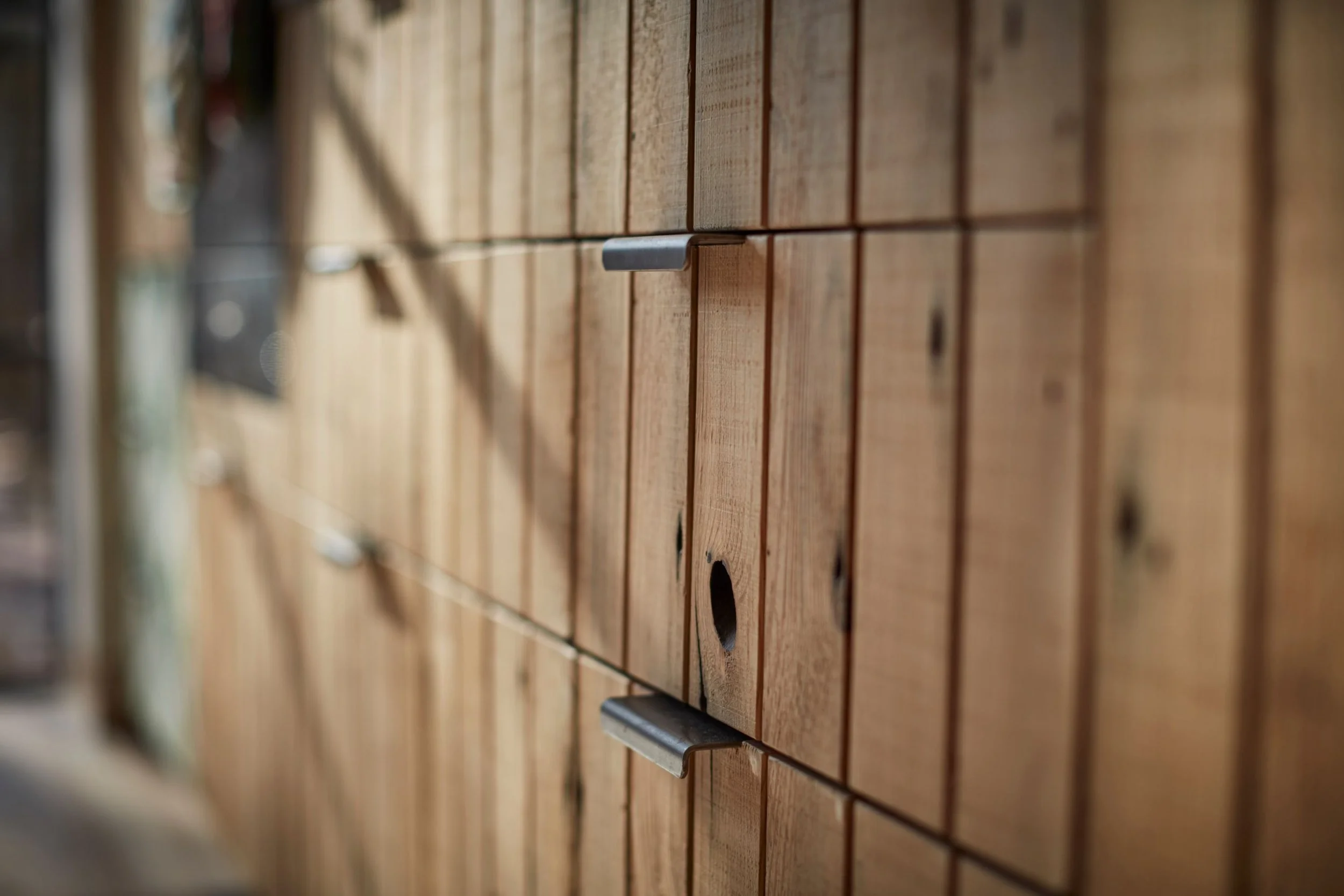 Close-up of a wooden cabinet with metal handles and circular holes in the wood panels.