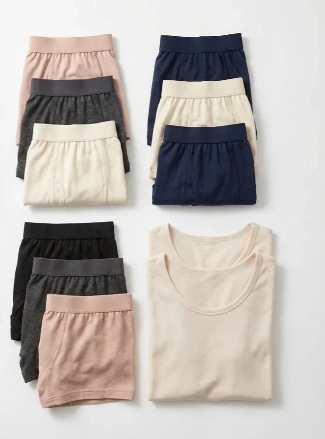 Folded beige, navy blue, dark gray, and light pink underwear arranged on a white surface, with two beige T-shirts folded on the right.