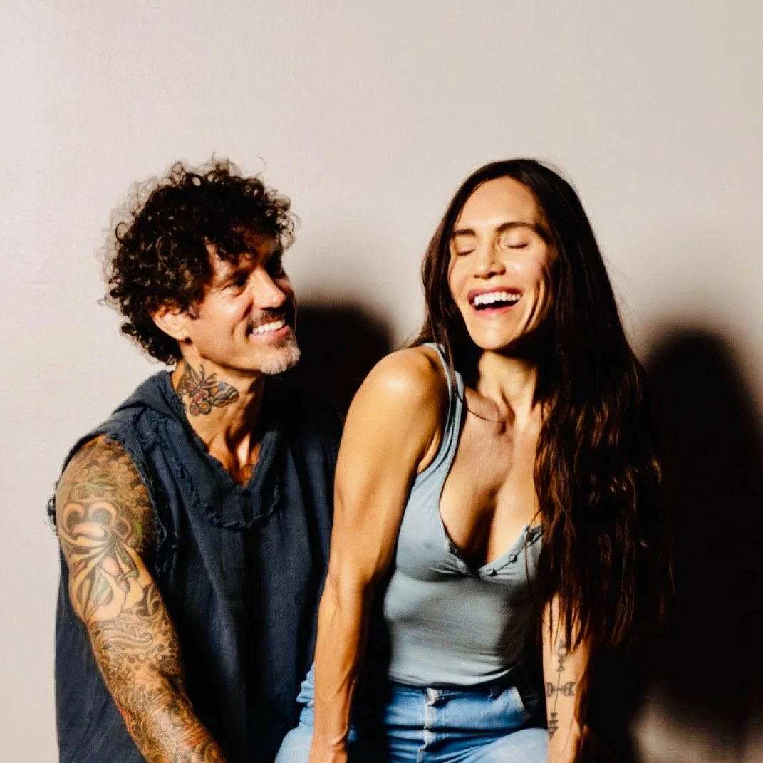 Mark Herron and Erinn Arizcorreta, Founders of Sukha Yoga Austin sitting together in their South Austin Location. Smiling and relaxed.