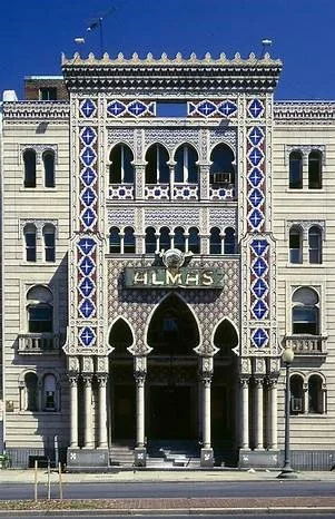 Historical building with intricate white and blue detailing, arched windows, and a large entrance with columns, labeled 'ALMAS'.