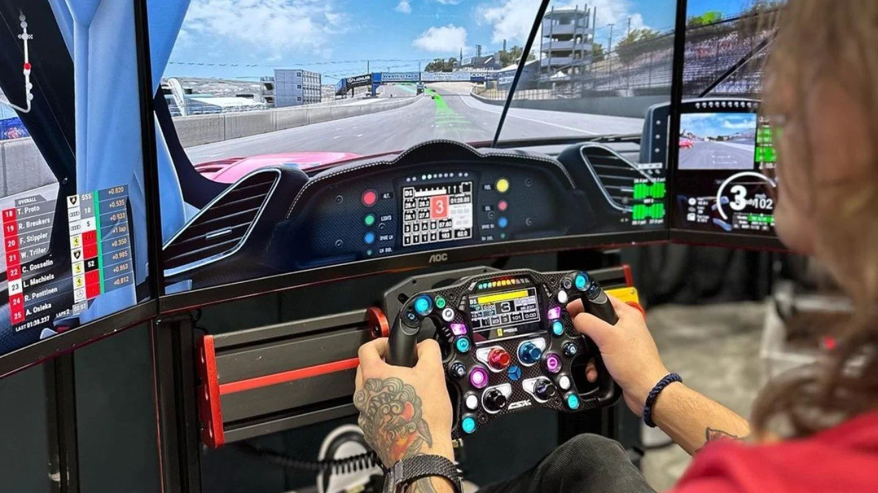 Person playing a racing simulator with a steering wheel and multiple monitors showing a racetrack.