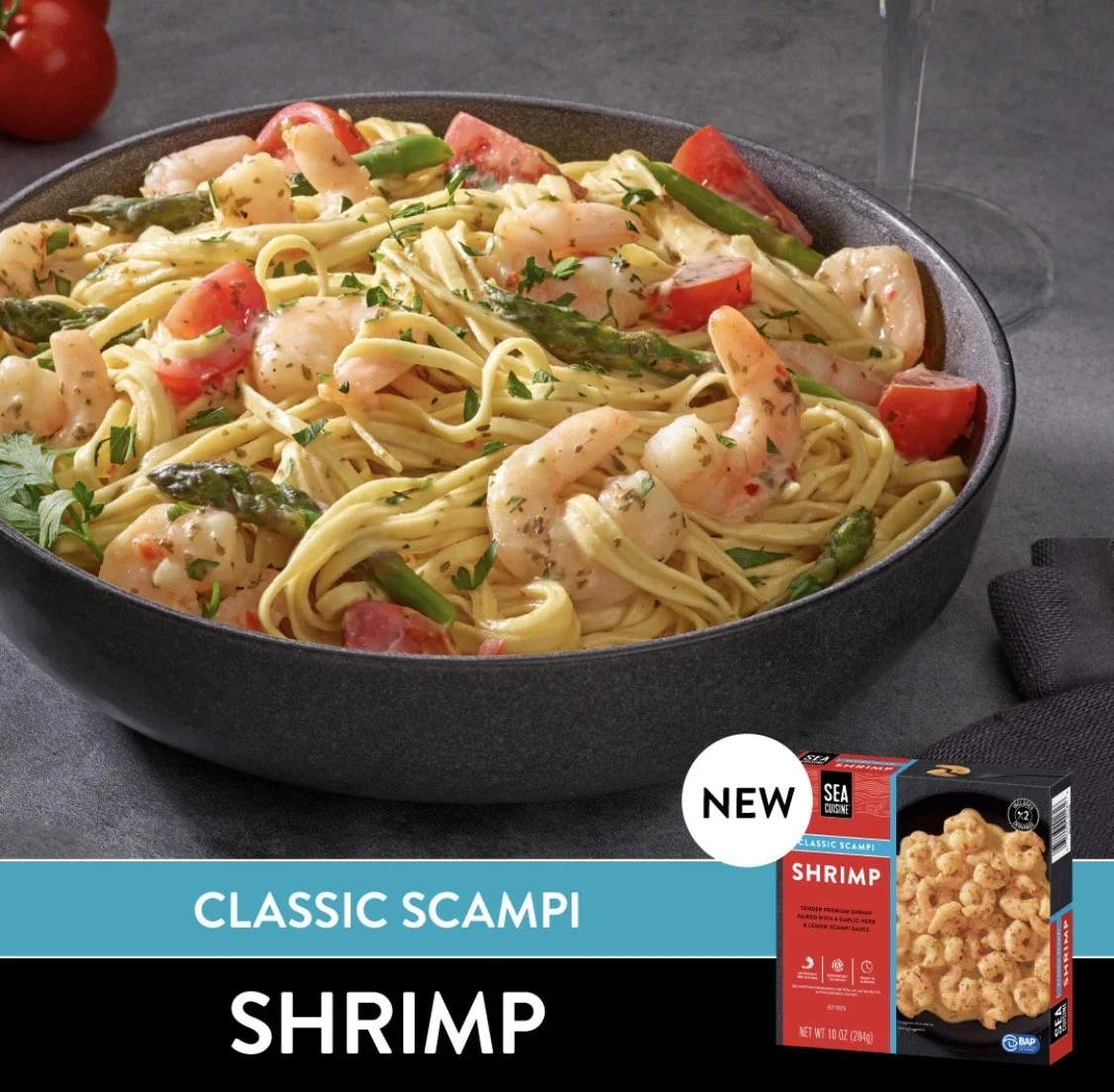 A bowl of pasta with shrimp, cherry tomatoes, and asparagus garnished with herbs. In the lower right corner, there's a box of Sea Cuisine classic scampi shrimp.