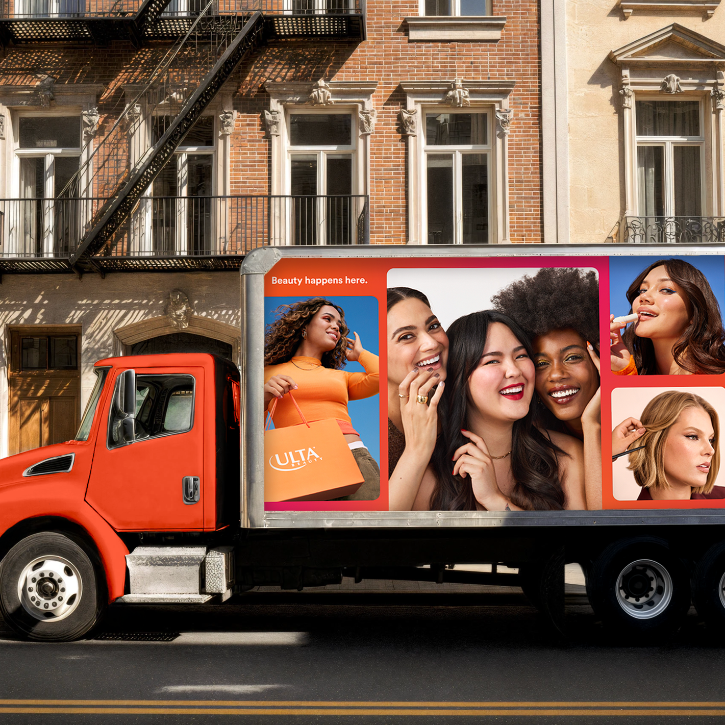 A red marketing truck with pictures of diverse women smiling and having fun, advertising beauty products, parked on a city street in front of brownstone buildings.