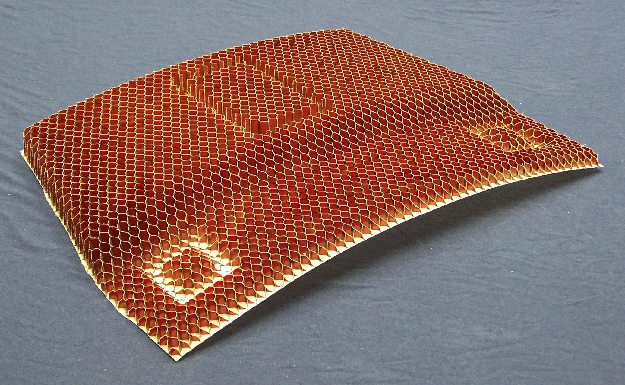 Close-up of a rectangular honeycomb-shaped object with a pattern and a small square cutout, placed on a dark surface.