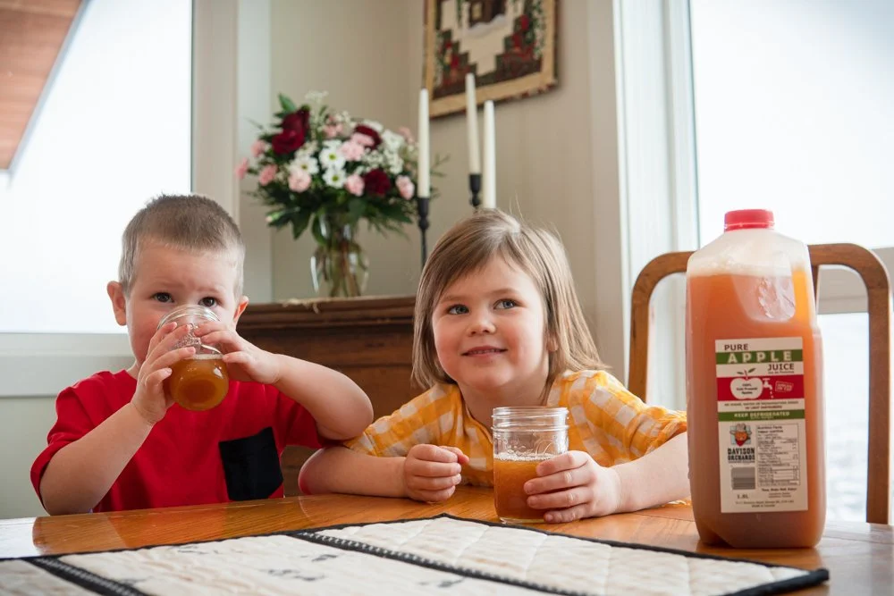 Two children drinking fresh cold pressed apple juice at Davison Orchards in Vernon BC, Okanagan Valley