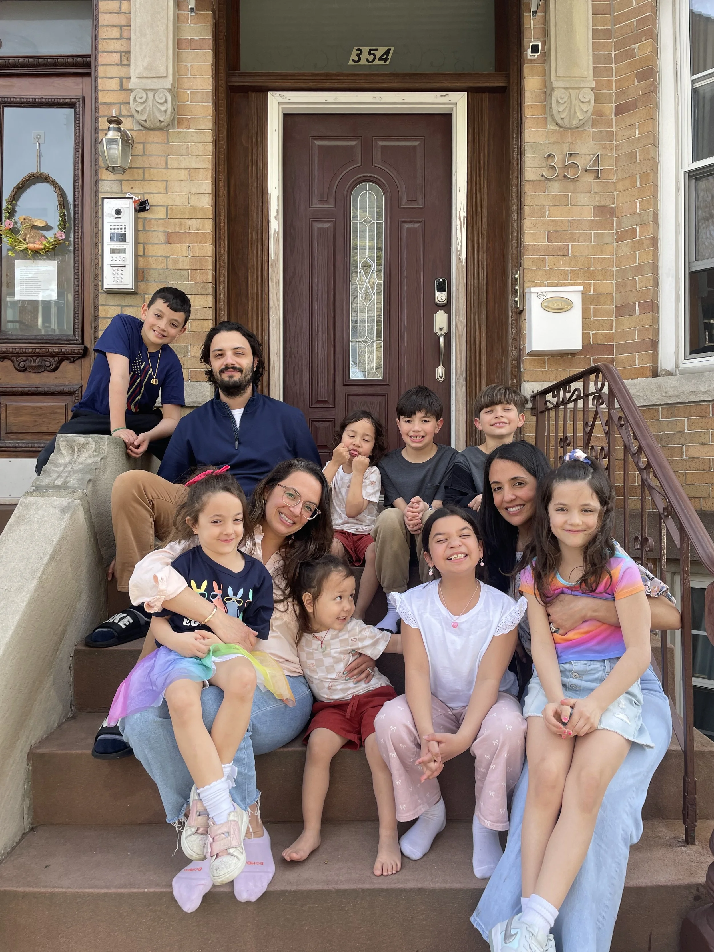 Family and children sitting on front steps of their house, smiling for a group photo.