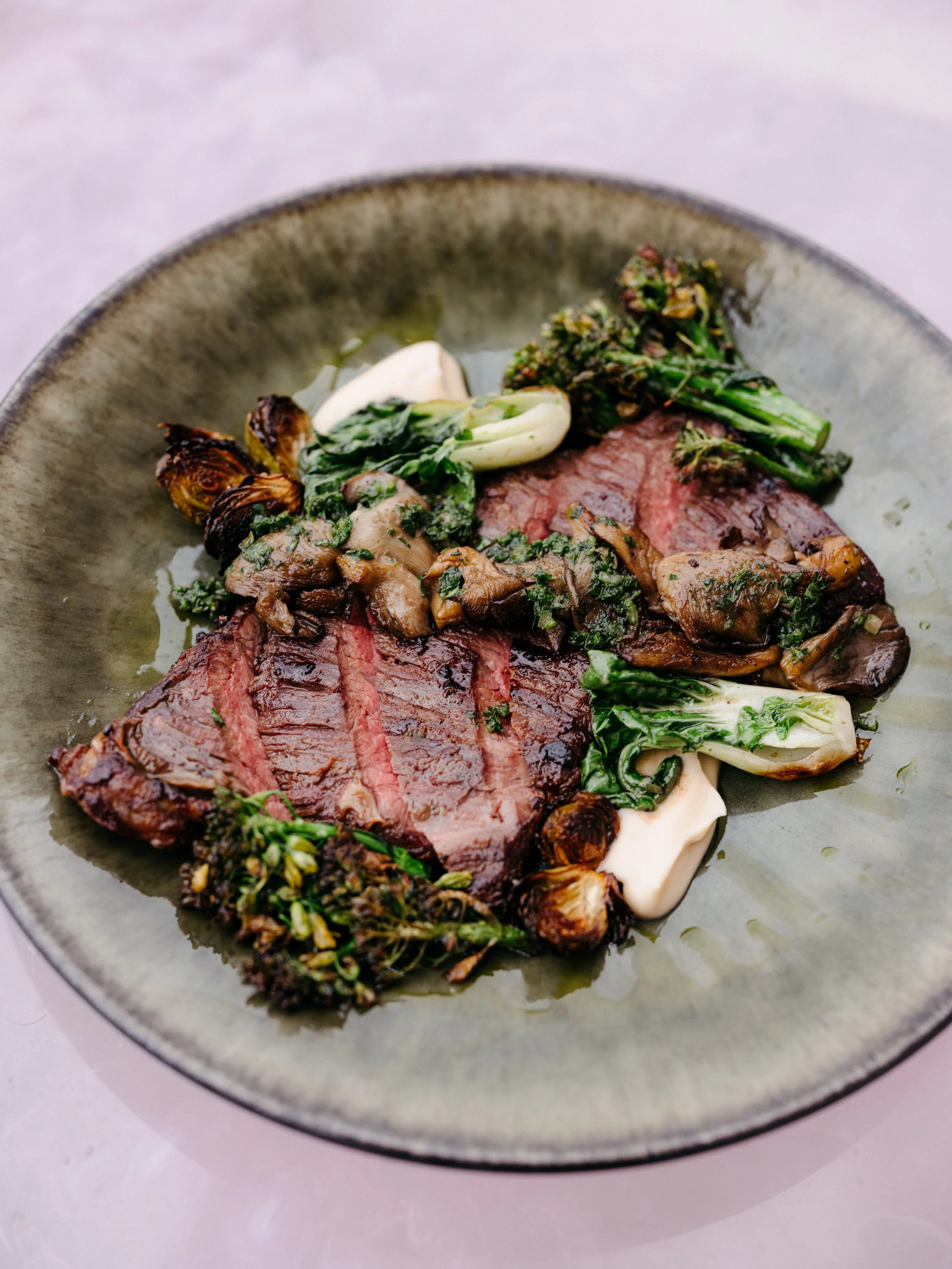 A plate with cooked steak, grilled vegetables, and greens.