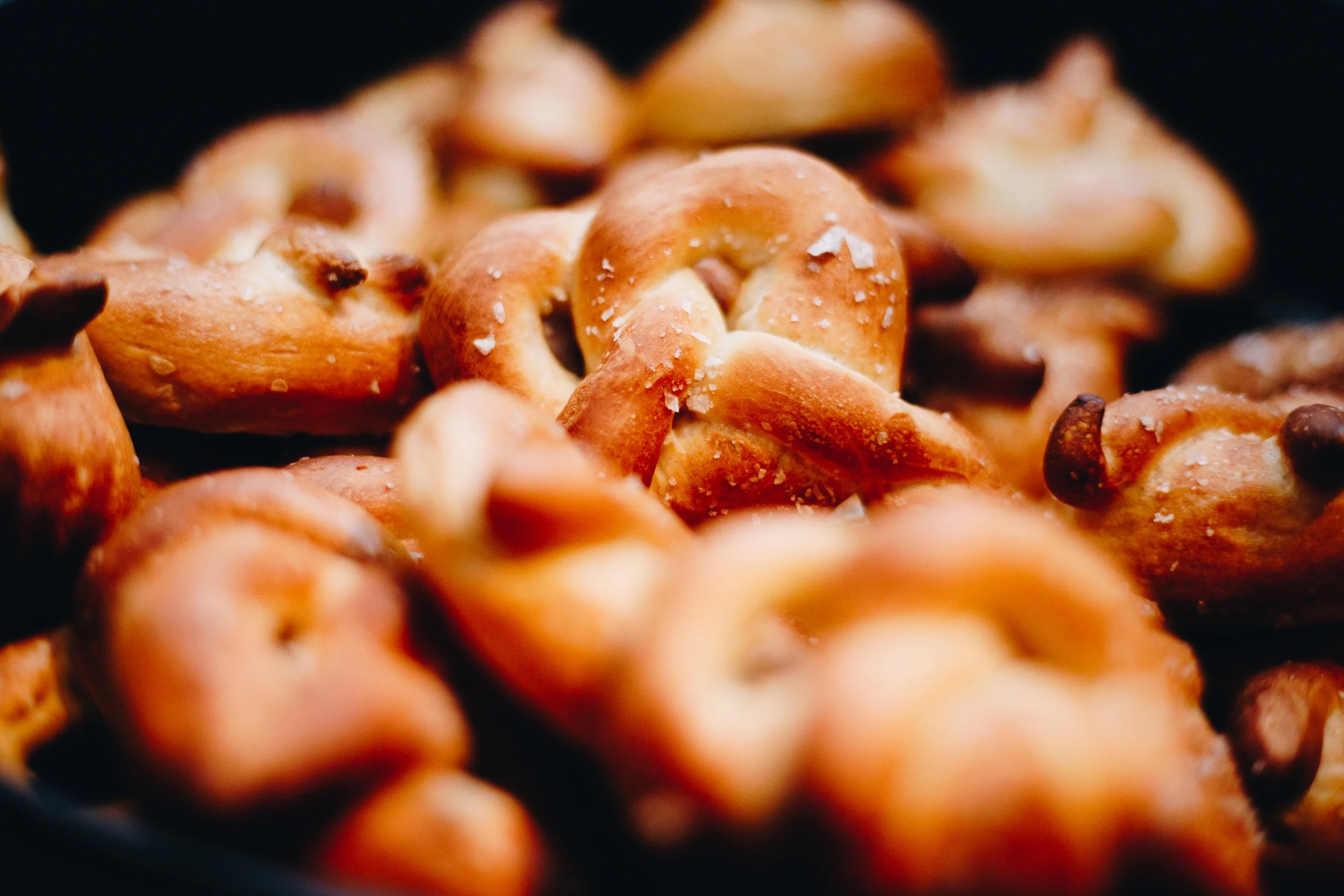 Close-up of salted roasted pretzels with salt crystals on surface.